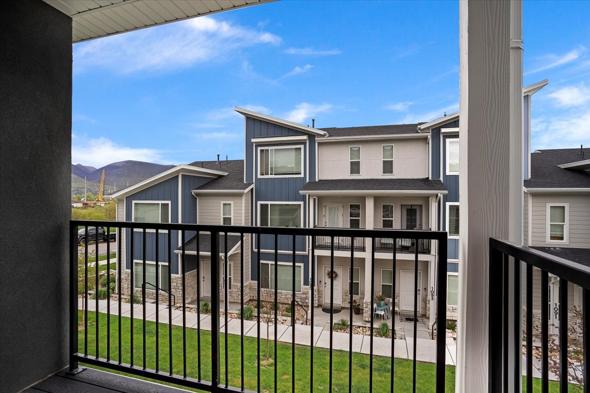 Exterior balcony with black metal railing overlooking a landscaped courtyard