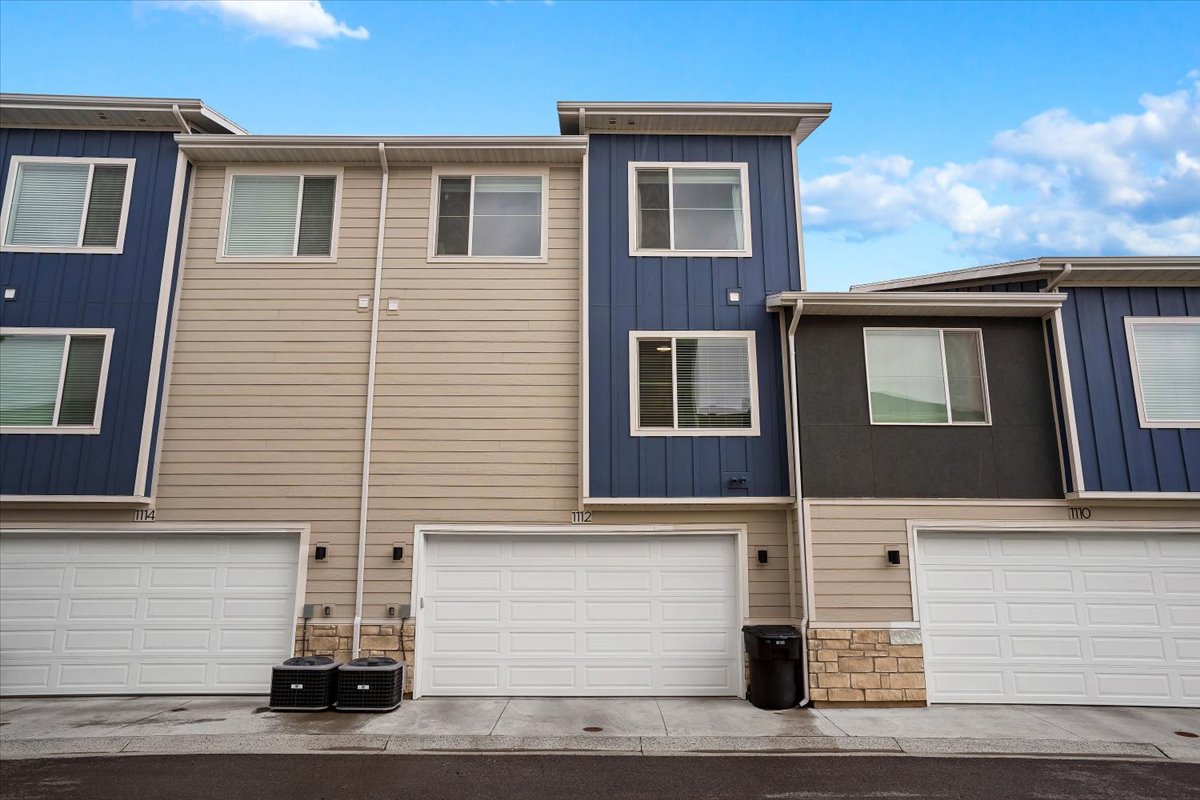 Contemporary townhome exterior featuring dual-tone siding, stone accents, two-car garage, and multiple windows