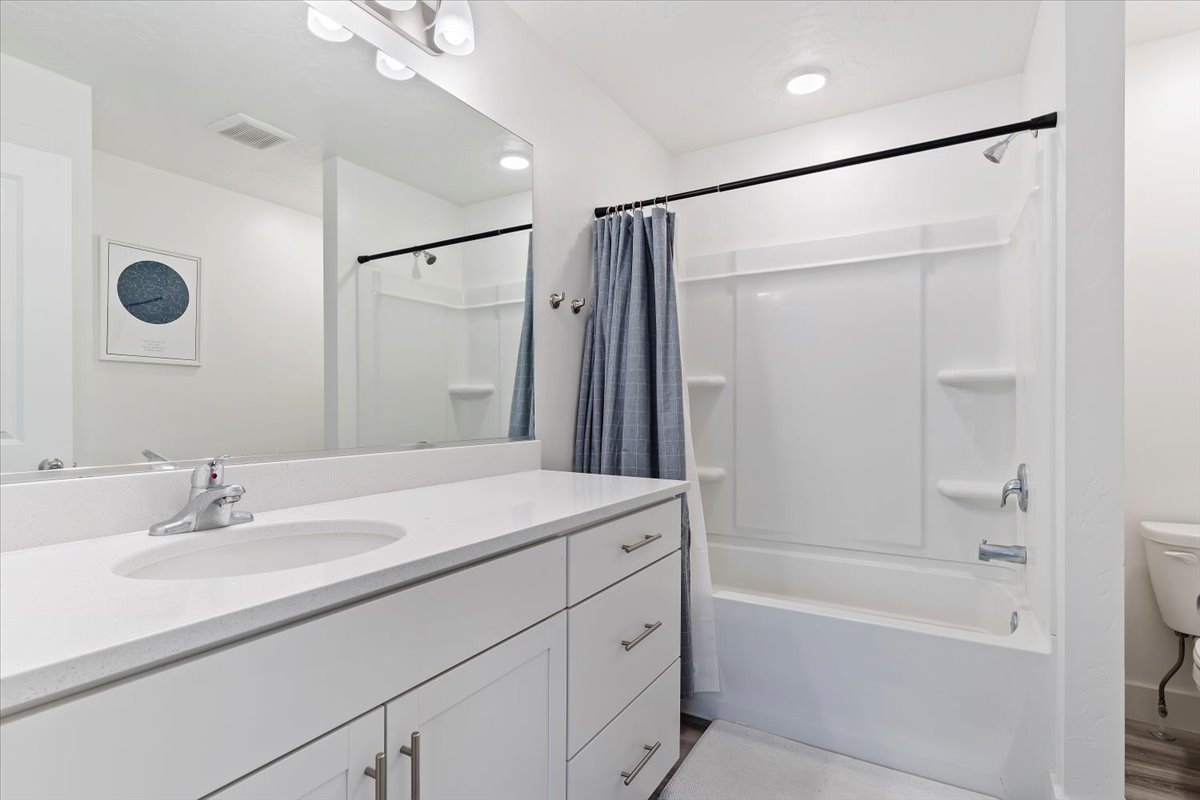 Bathroom featuring a single vanity with a white countertop and integrated sink, chrome faucet, and white cabinetry with drawer storage