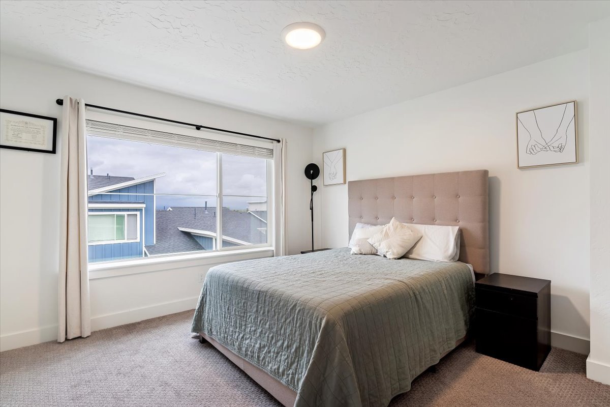 Spacious room featuring a large horizontal window with white trim, light-colored carpeting, white walls, and a contemporary flush-mount ceiling light