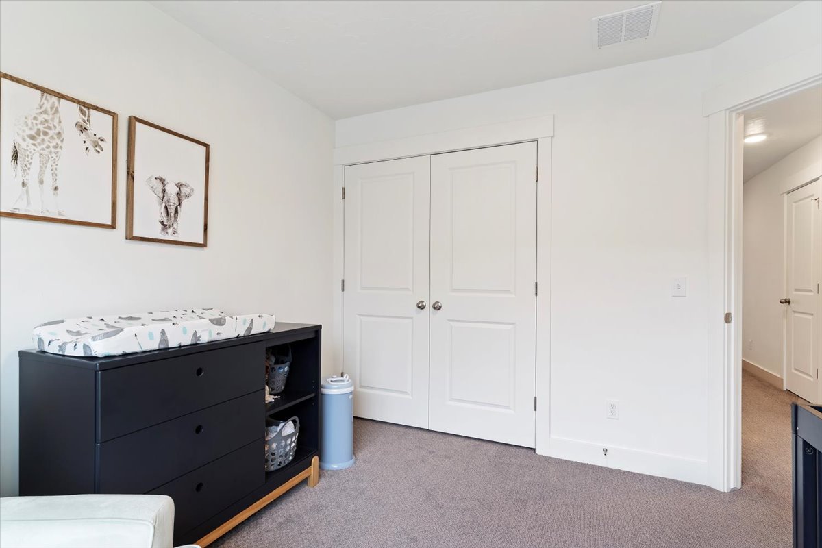 White interior walls featuring a pair of bifold doors, neutral carpeting, and white baseboards