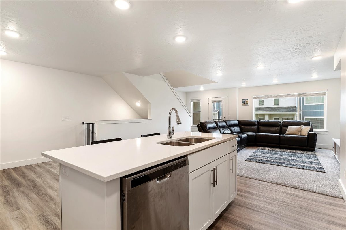 Kitchen island featuring a double-basin stainless steel sink, gooseneck faucet, and integrated dishwasher