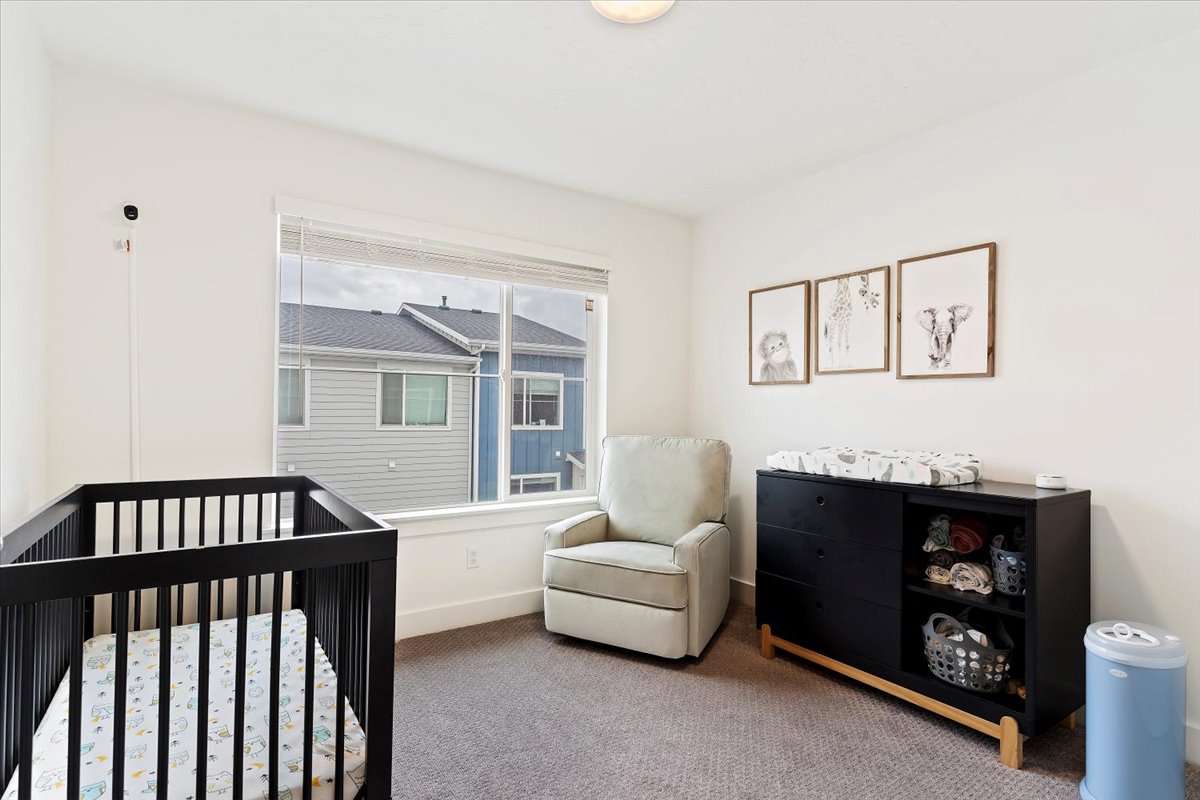 Bright room featuring a large window with blinds, neutral wall paint, and gray carpet flooring