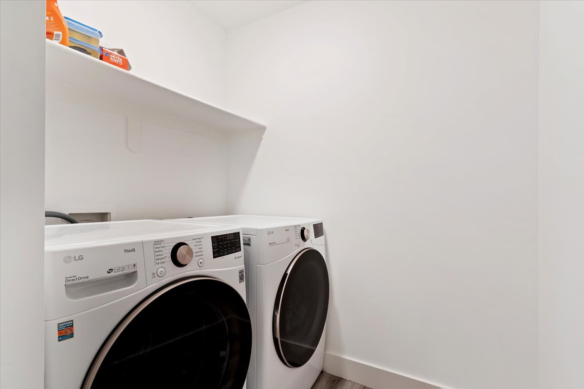 Laundry area featuring a built-in shelf, white walls, and wood-finish flooring