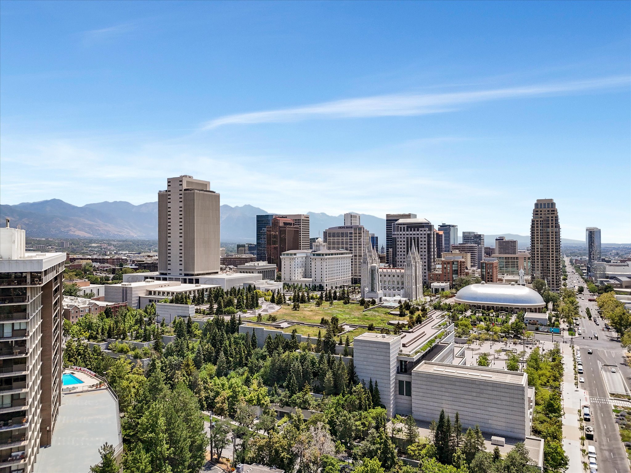 Expansive city skyline with prominent high-rise structures, featuring a distant mountain range backdrop