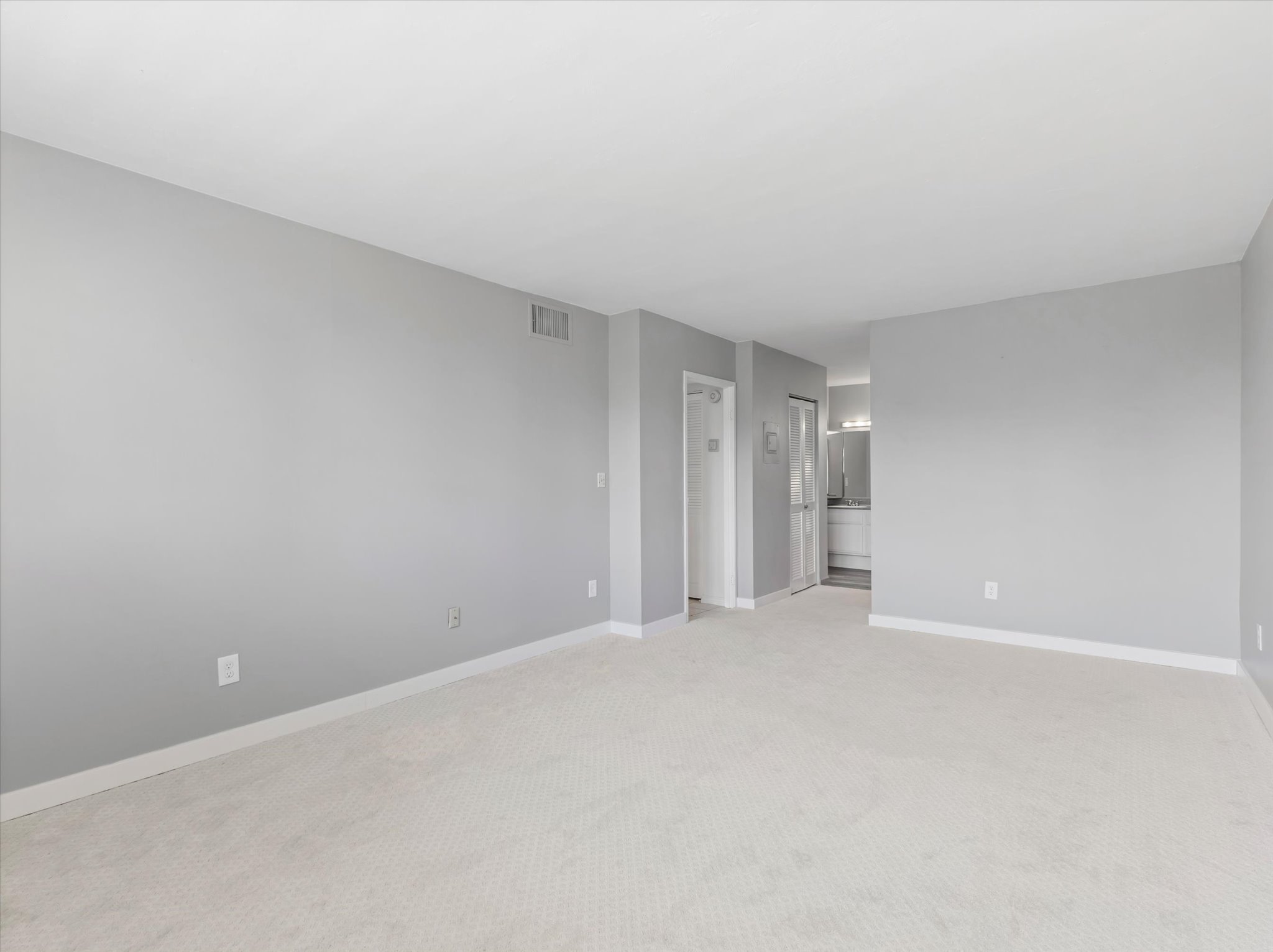 Spacious room with light gray walls and white baseboards