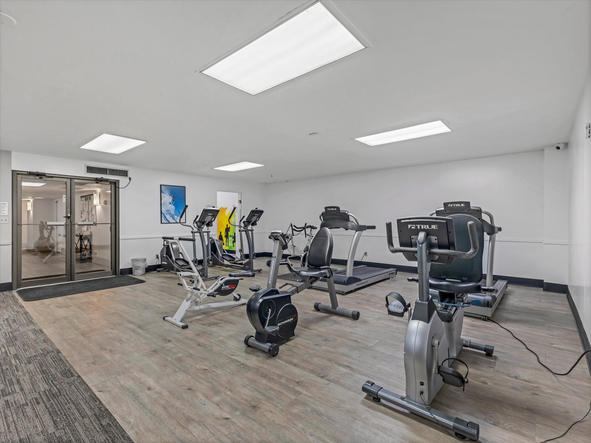 Fitness center featuring wood-finish flooring, recessed lighting, and a variety of exercise equipment
