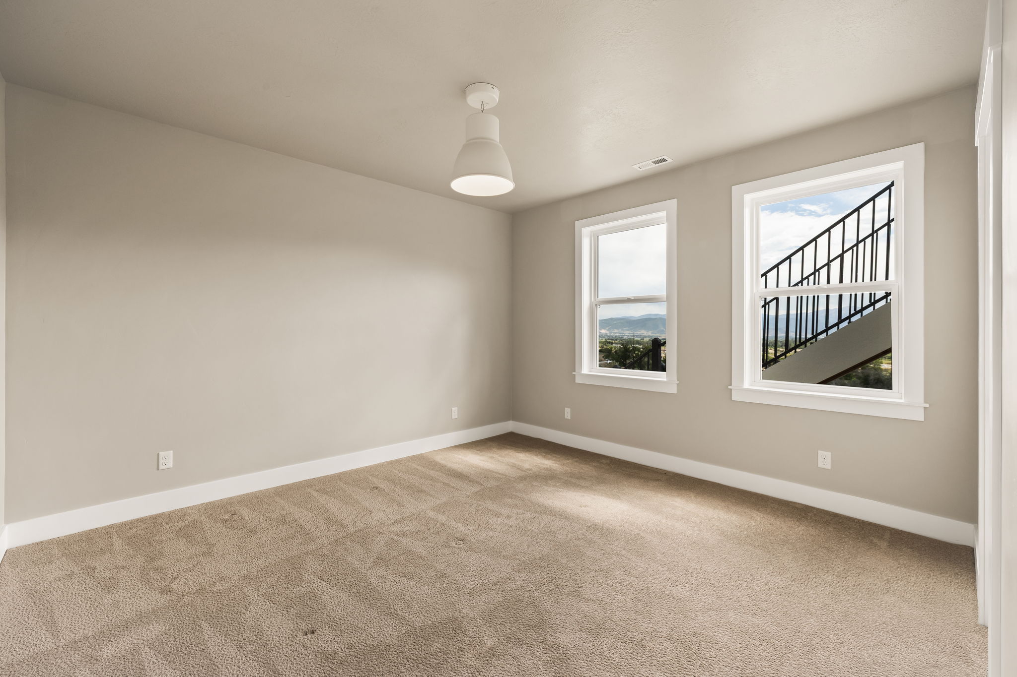 Carpeted room featuring two double-hung windows, a white ceiling fixture, and light-toned wall paint