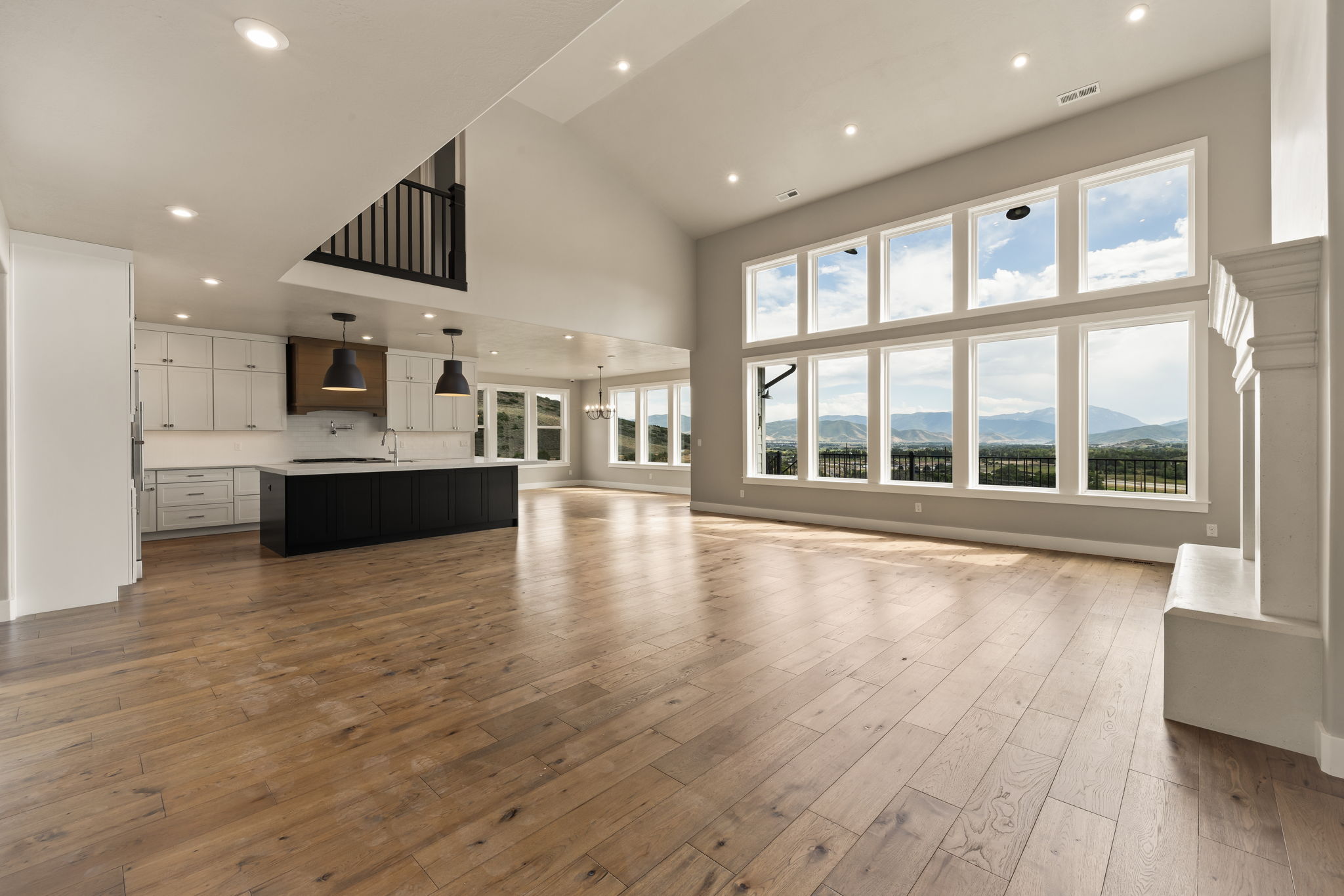 Vaulted ceiling living space with wood-finish flooring, a contemporary fireplace, and floor-to-ceiling windows