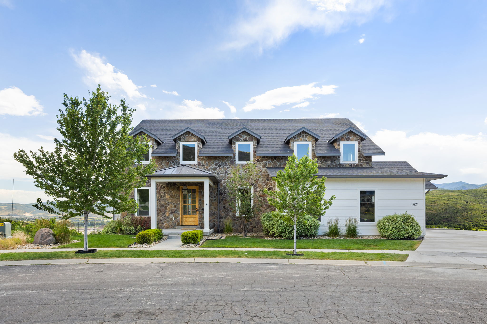 Stone and siding exterior with dark shingle roof and dormer windows