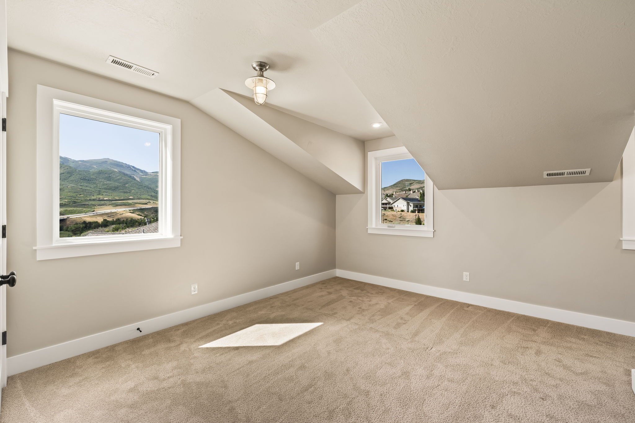 Carpeted room featuring sloped ceilings, two windows with white trim, and a semi-flush mount light fixture