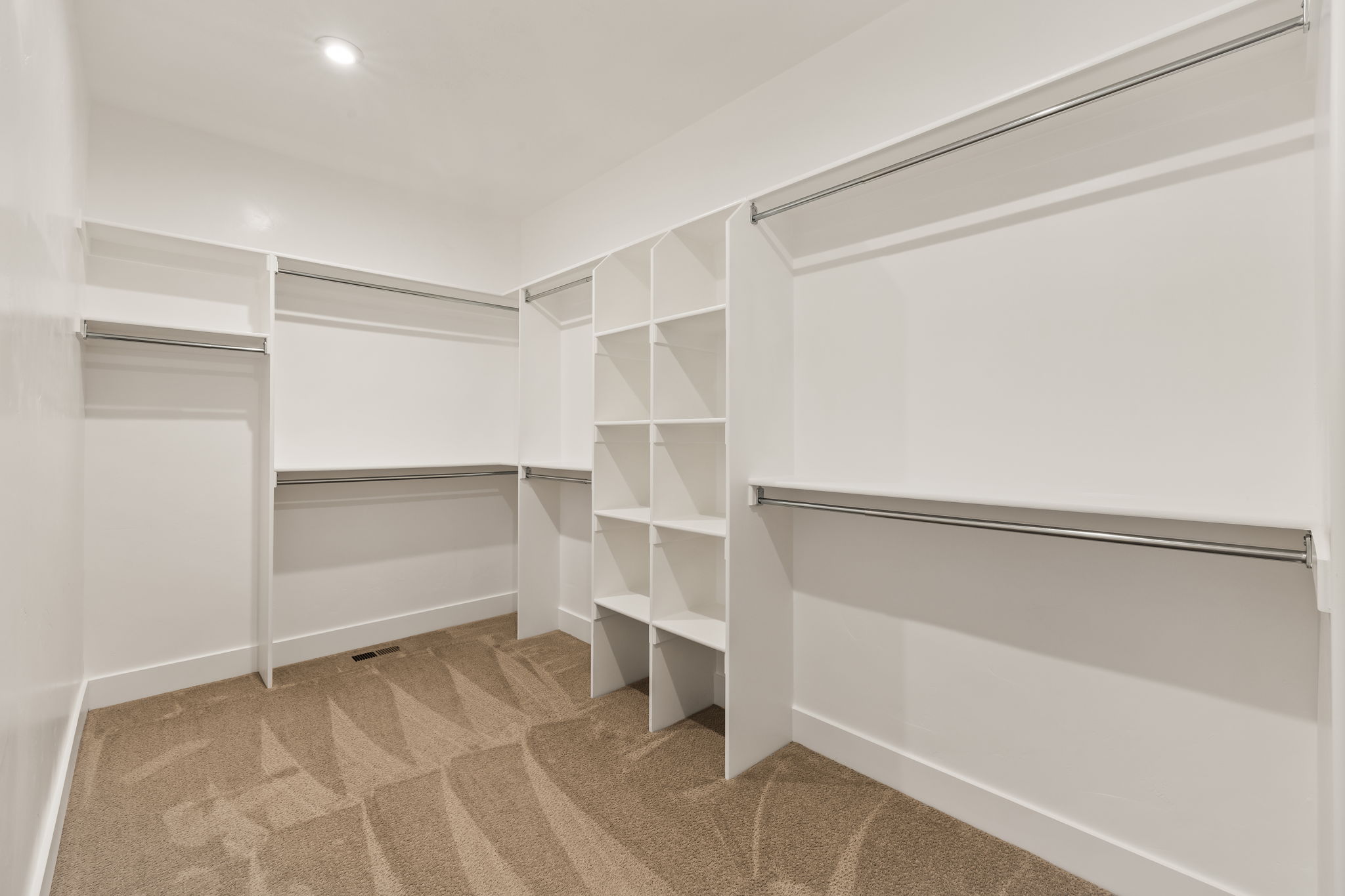 Spacious walk-in closet featuring built-in shelving, multiple hanging rods, and recessed lighting