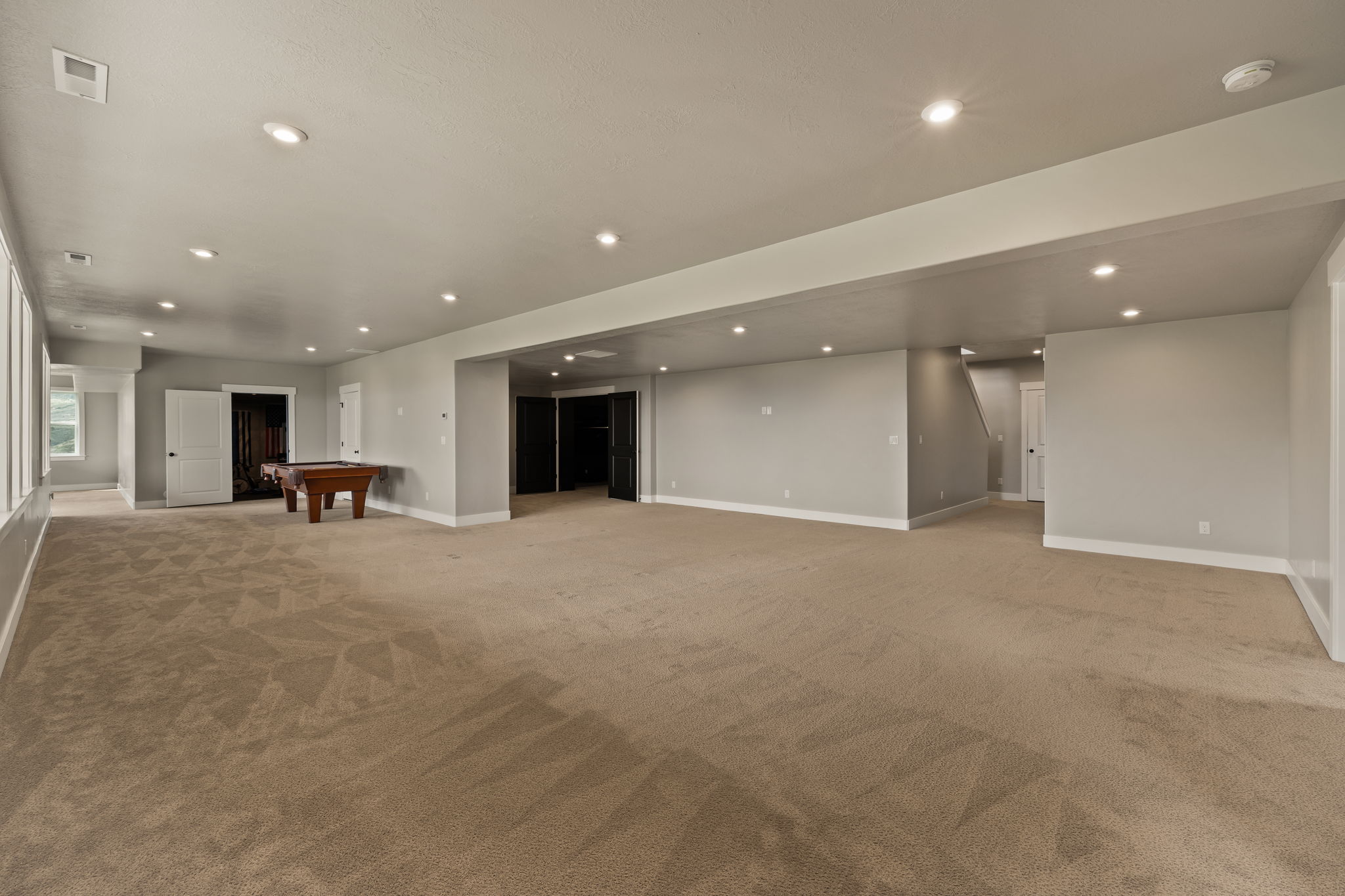 Expansive finished lower level featuring recessed lighting, light gray painted walls, and tan carpeting