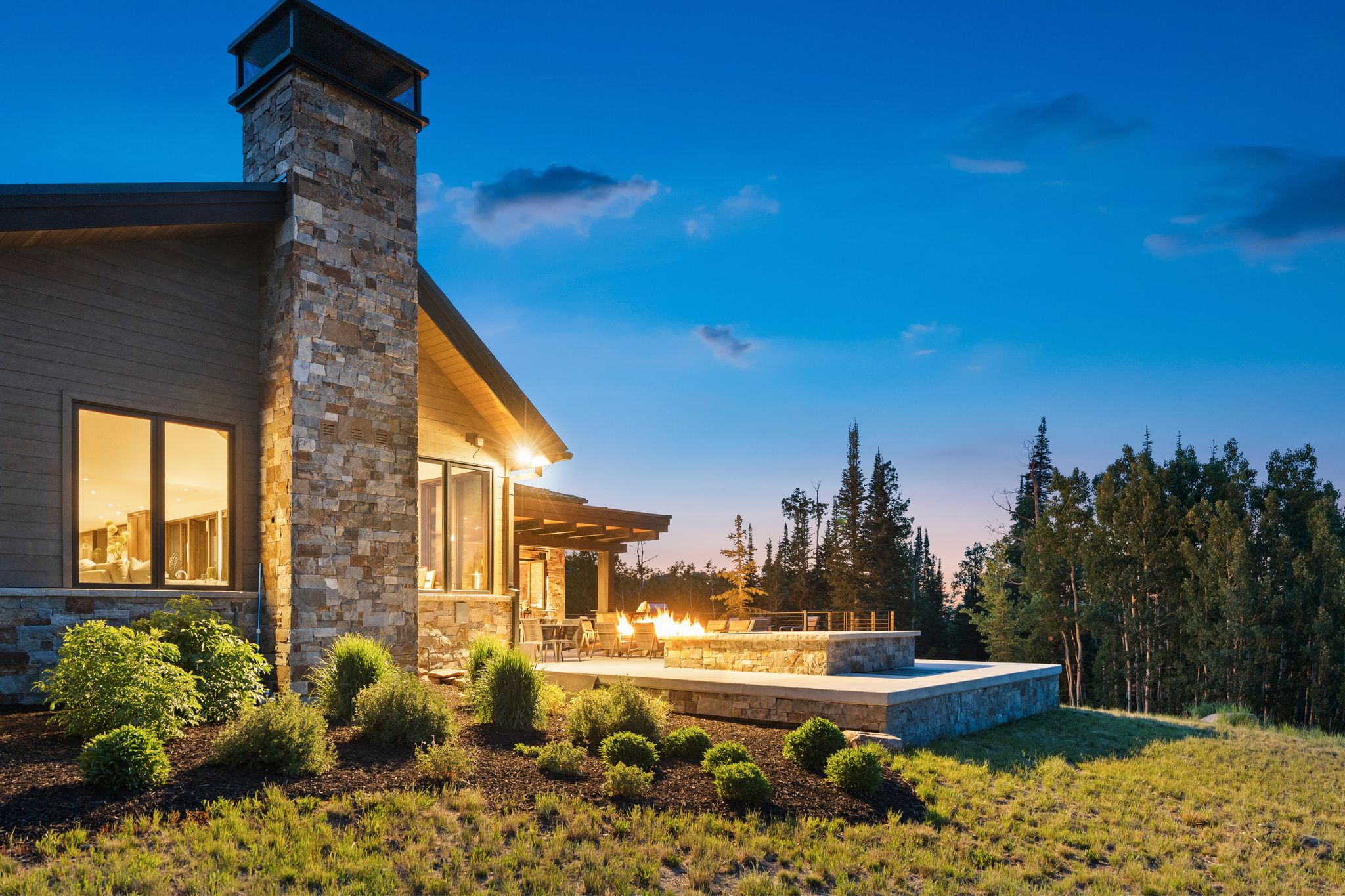 Stone-clad exterior featuring a prominent chimney, wood siding, and large windows