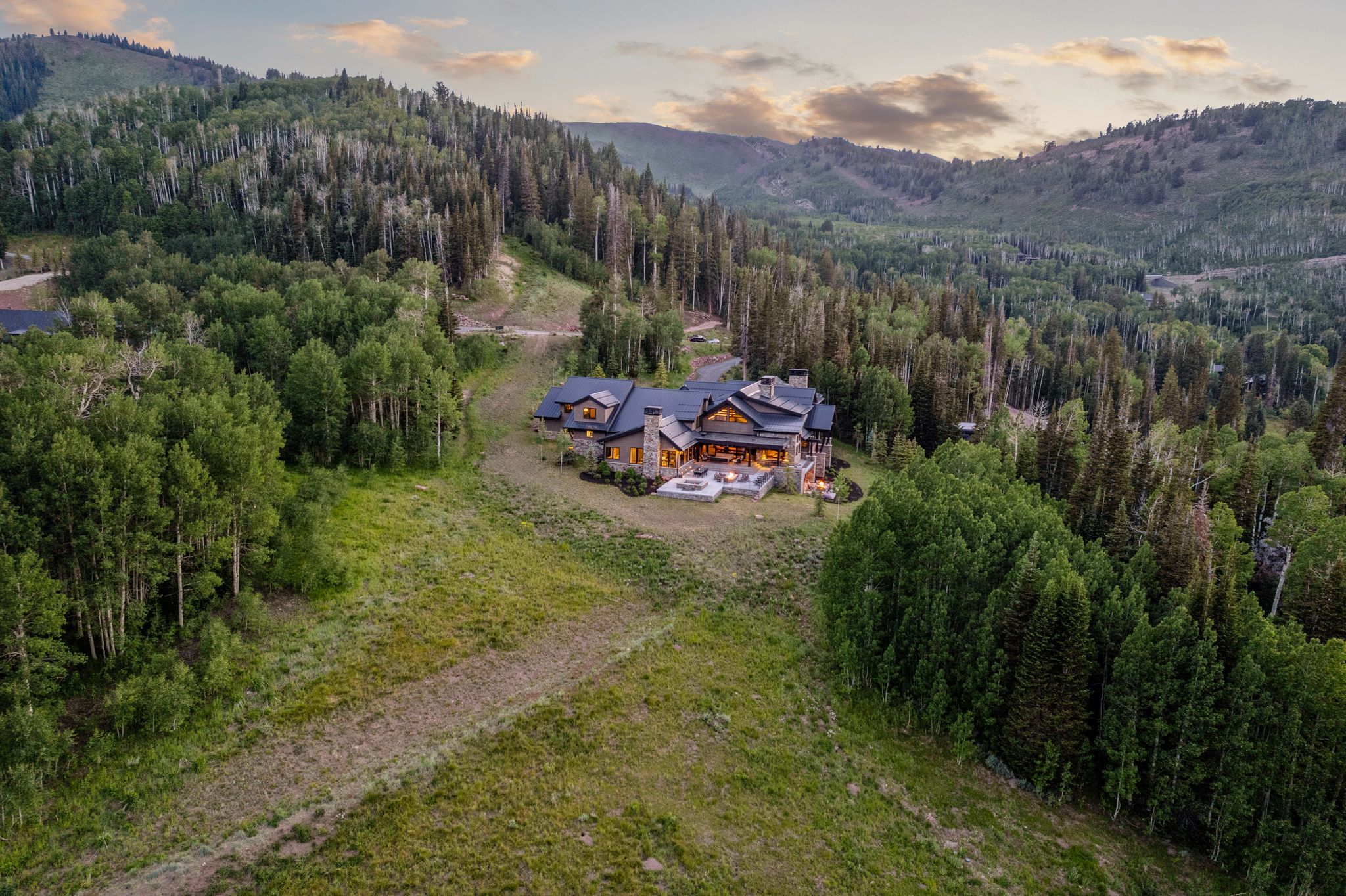 Expansive mountain property featuring a large residence with multiple gables, stone siding, and prominent chimneys