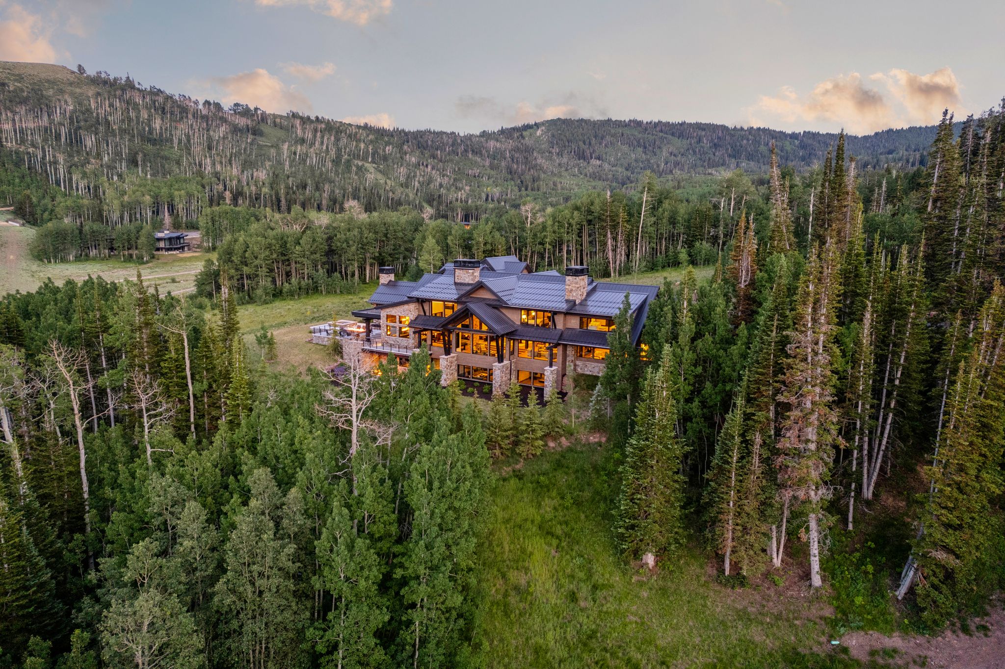 Architectural residence featuring stone and wood siding, multiple large windows, and a dark shingle roof