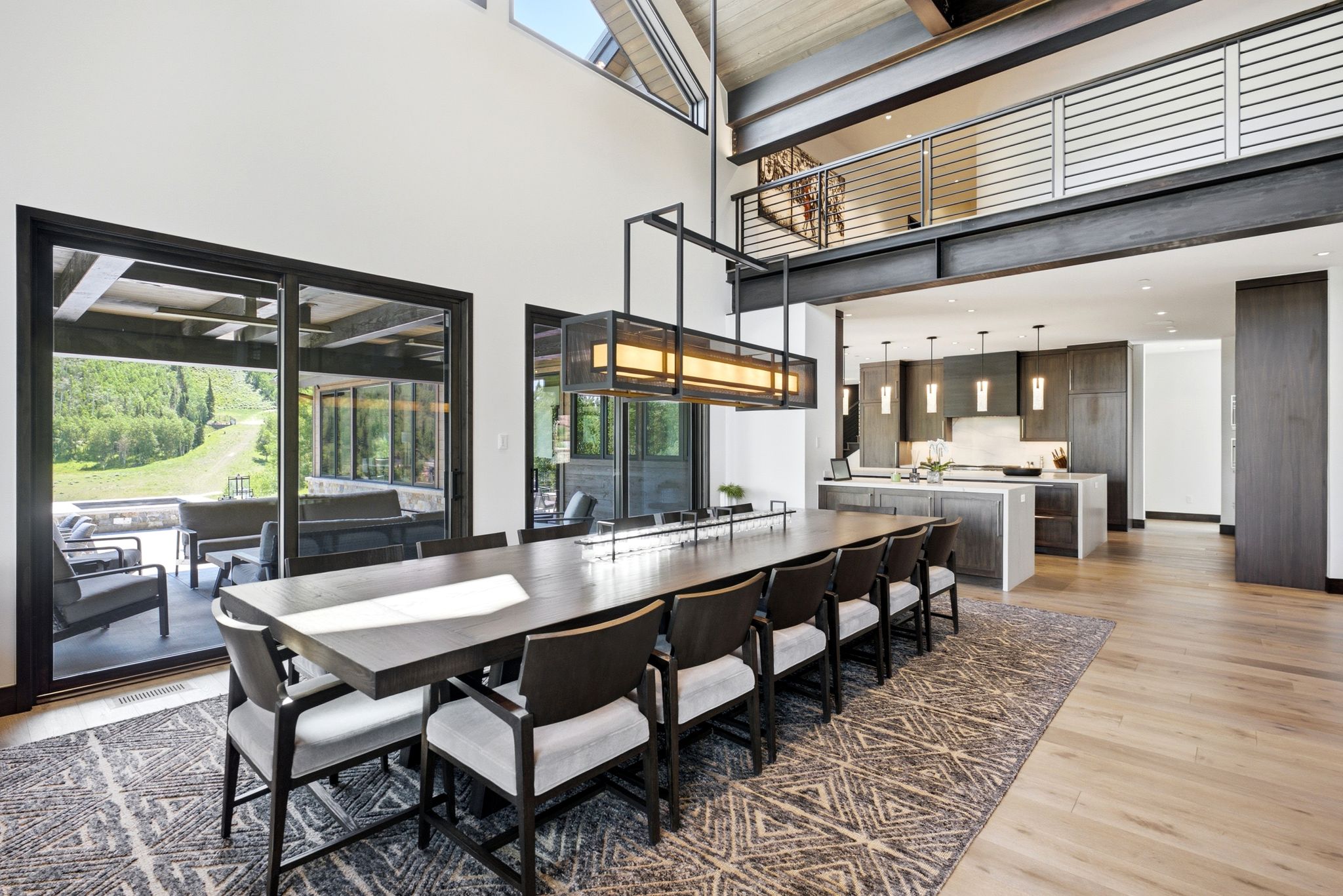 Spacious open-concept living area featuring high vaulted ceilings, exposed structural beams, and light wood-finish flooring