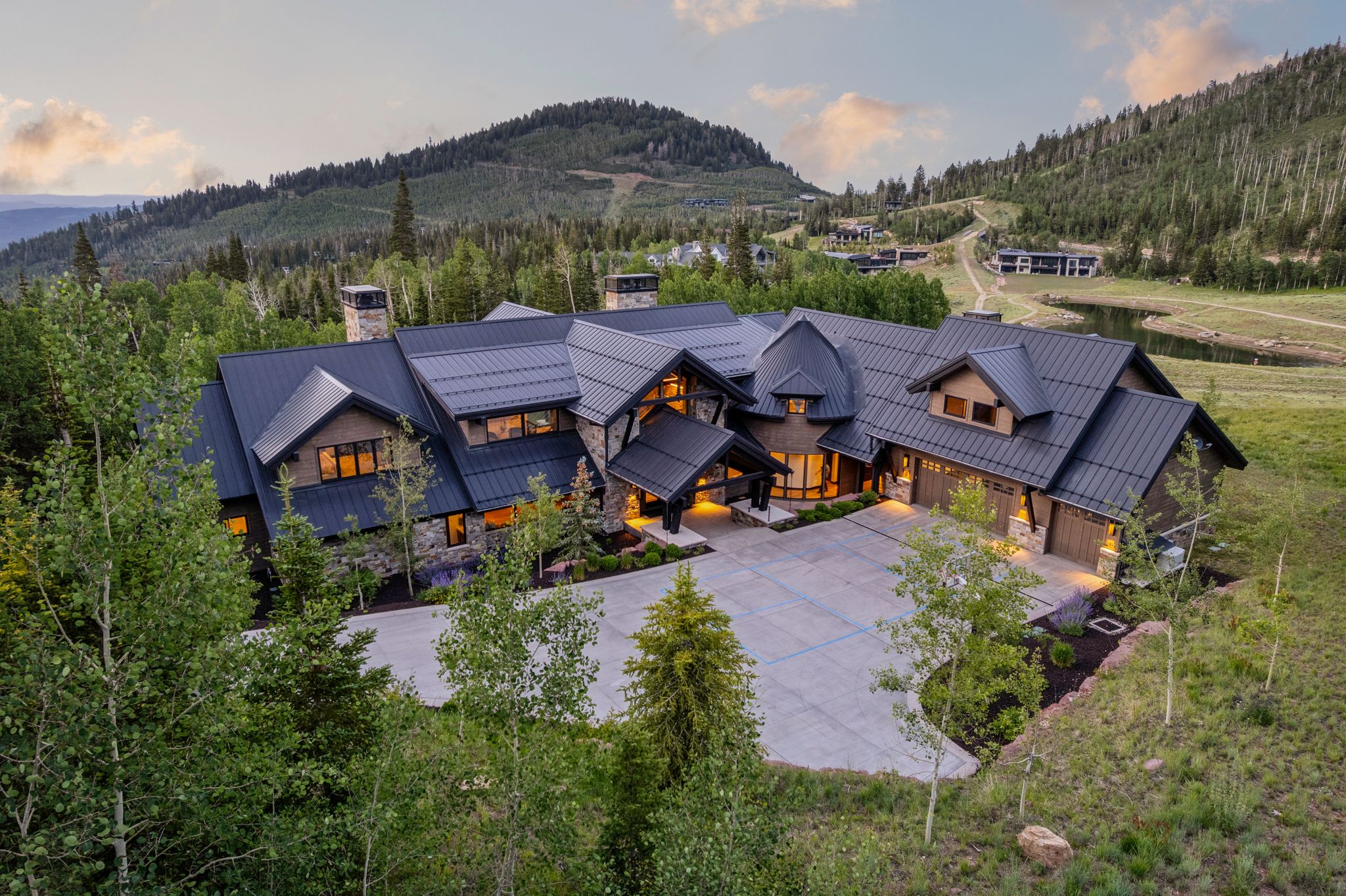 Expansive mountain property featuring a dark metal roof, stone and wood-panel exterior, multiple gables, and an integrated three-car garage