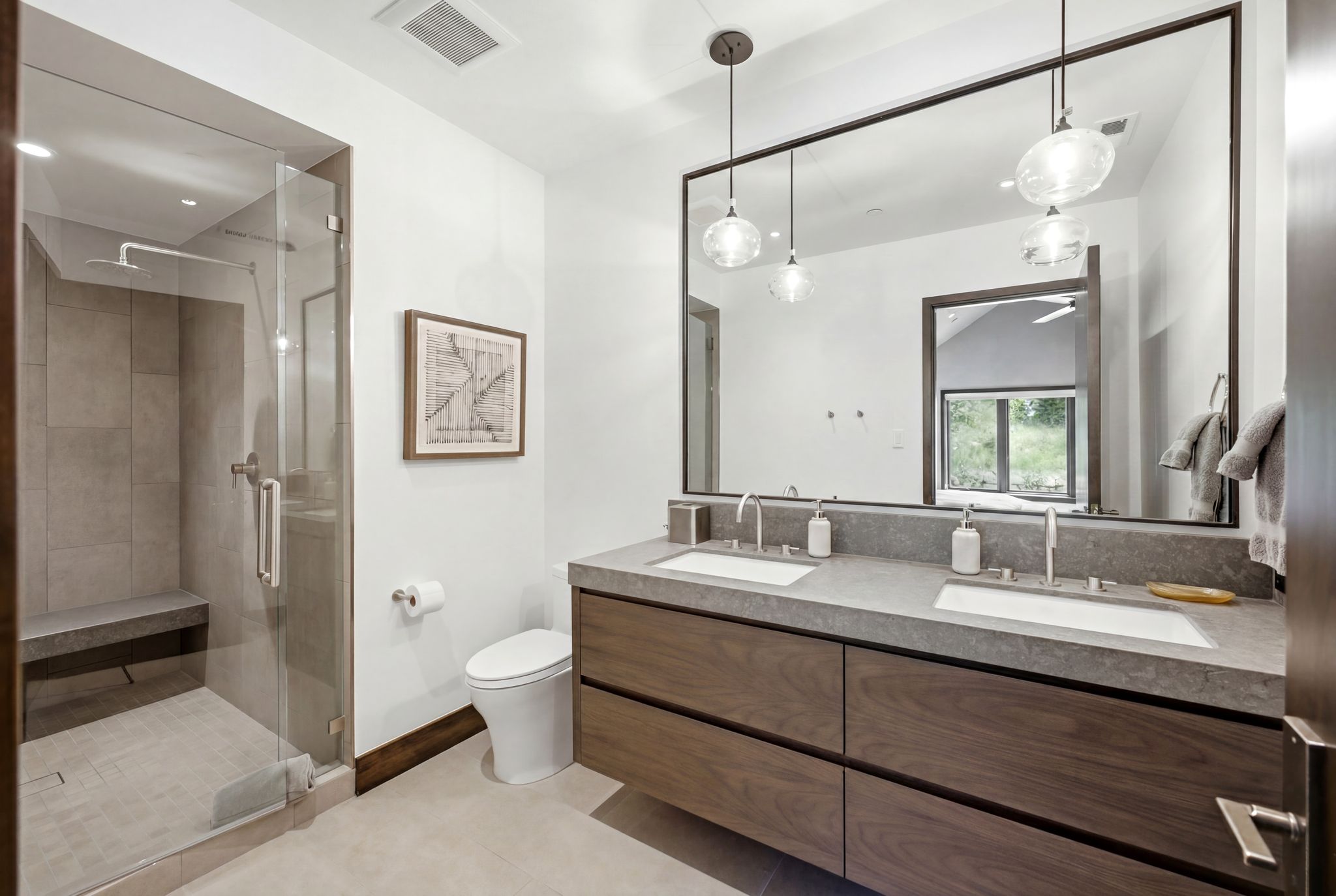 Contemporary bathroom featuring a dual vanity with wood-finish cabinetry and a stone countertop