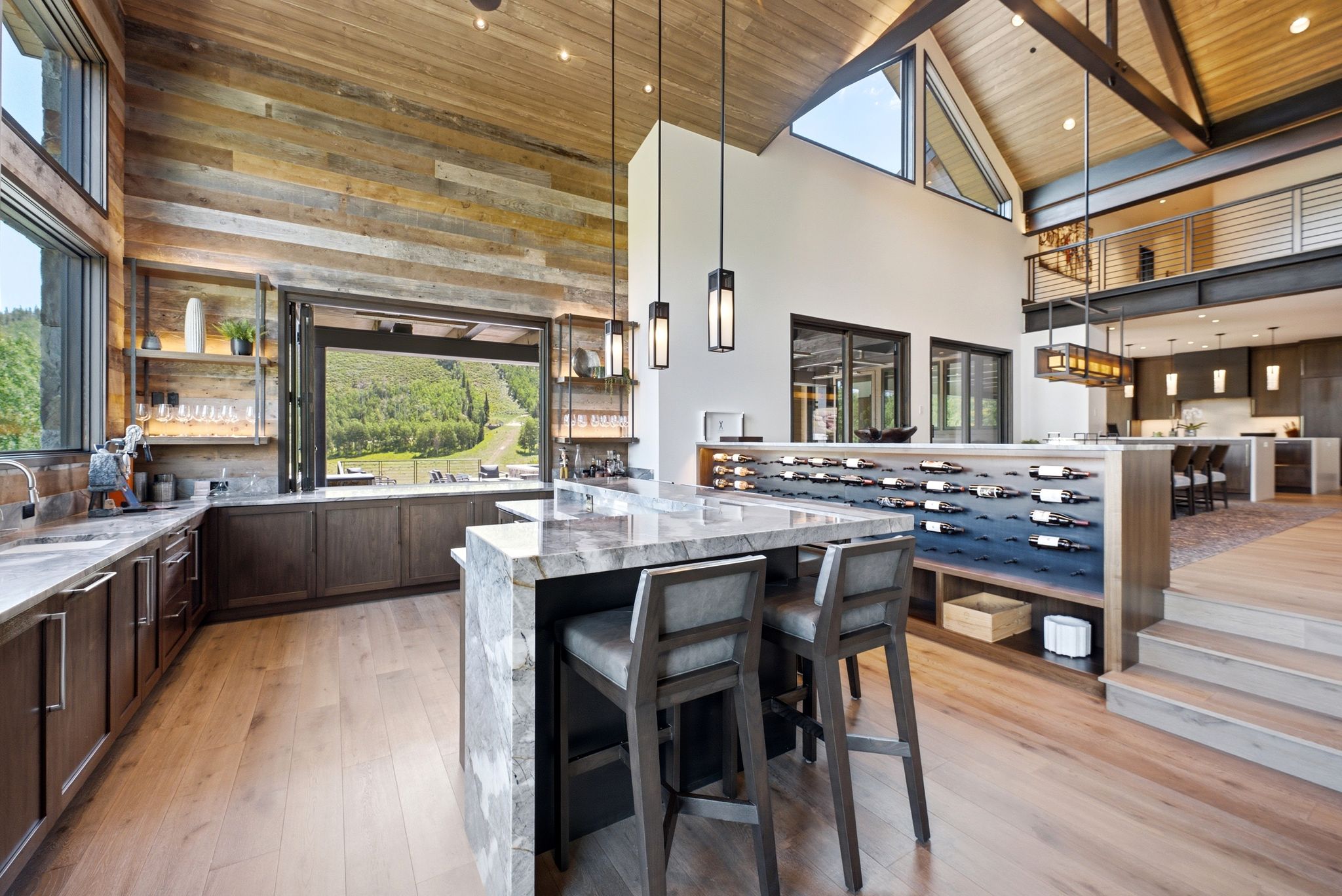 Open-concept interior featuring vaulted wood-clad ceilings with exposed beams, a large wood-finish flooring expanse, and a multi-level design