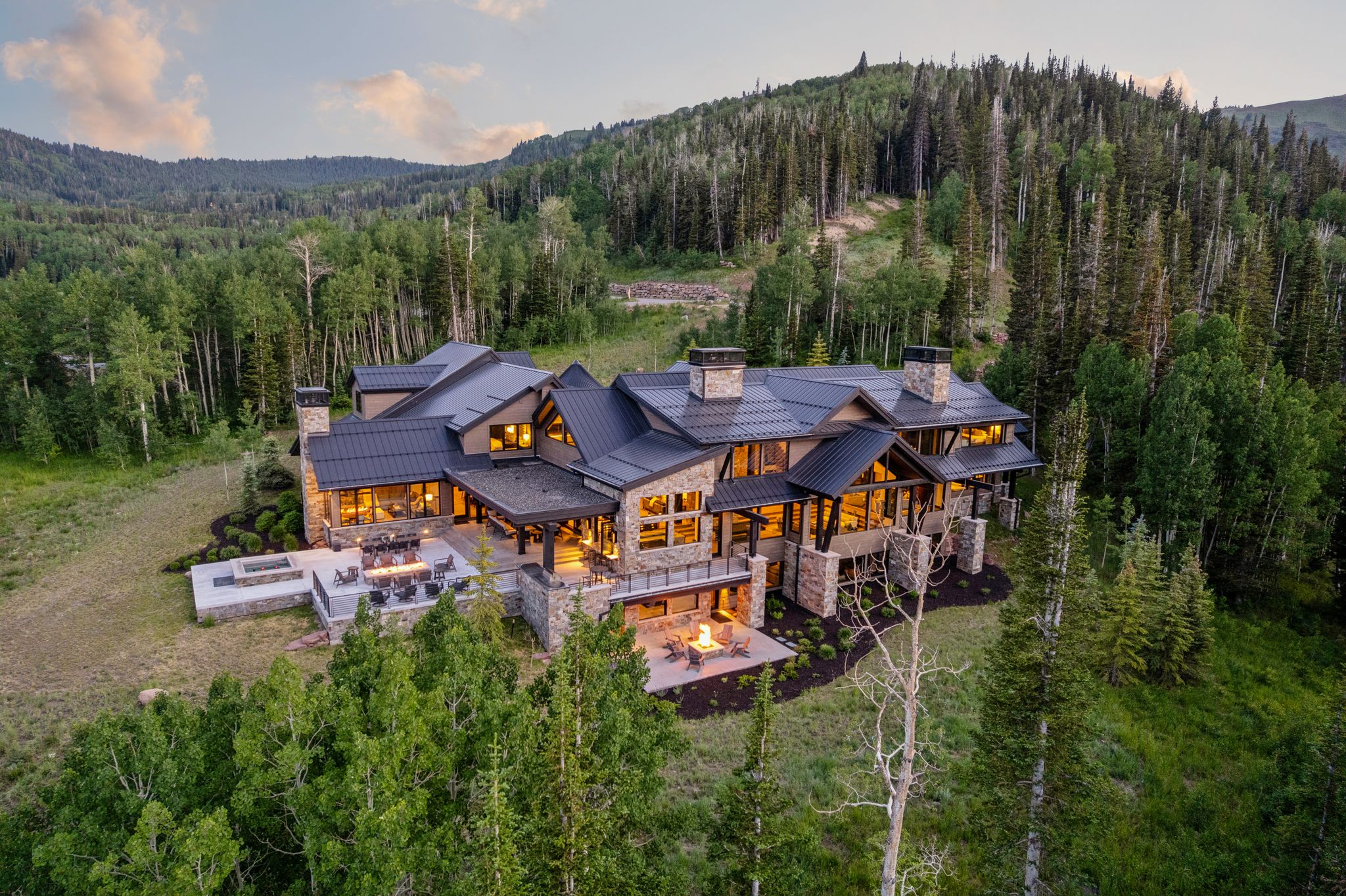 Expansive mountain retreat featuring a multi-level stone and wood exterior with a dark metal roof