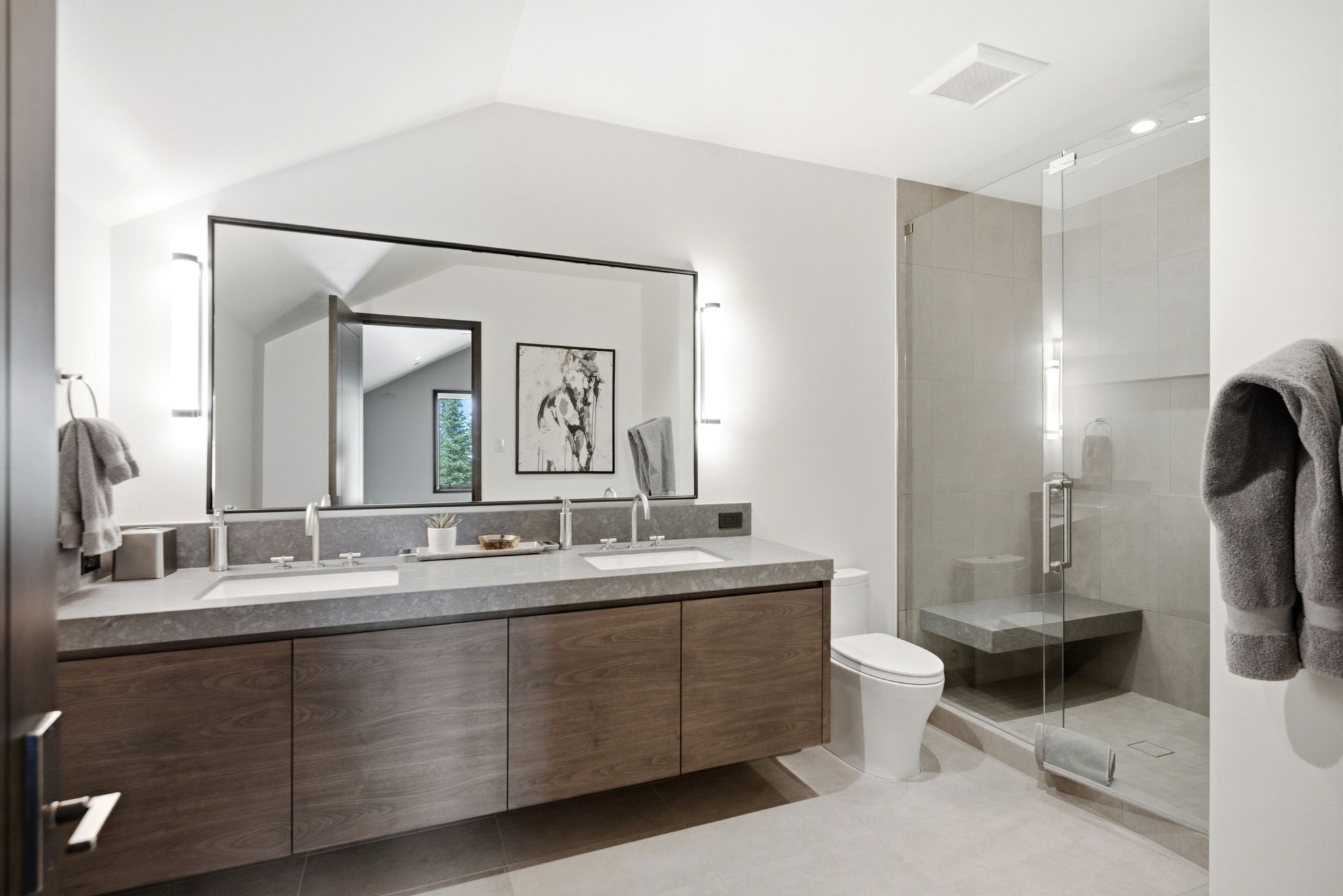 Contemporary bathroom featuring a floating dual vanity with a gray stone countertop, integrated sinks, and chrome faucets