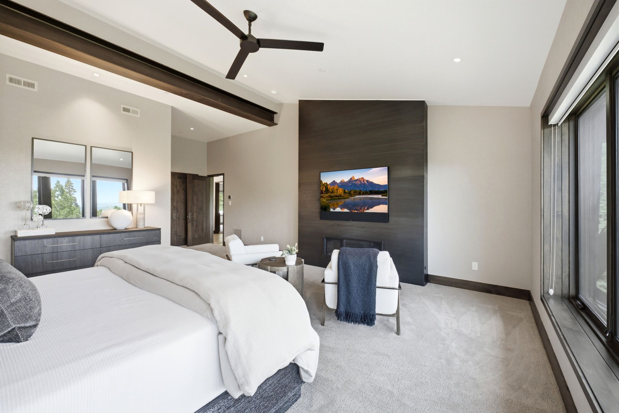 Spacious room featuring vaulted ceilings with exposed structural beams, recessed lighting, and a dark-toned ceiling fan