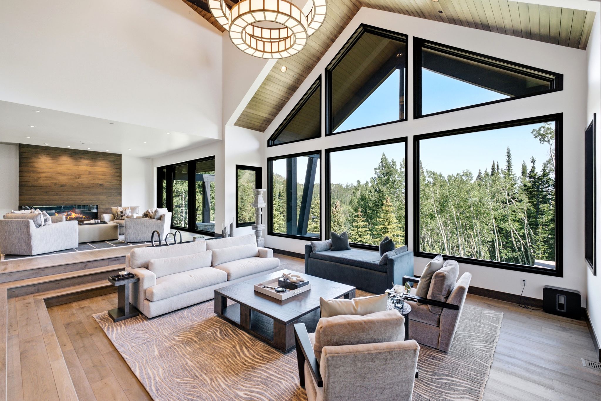 Vaulted living space featuring expansive floor-to-ceiling windows, wood-finish flooring, and a unique tiered layout