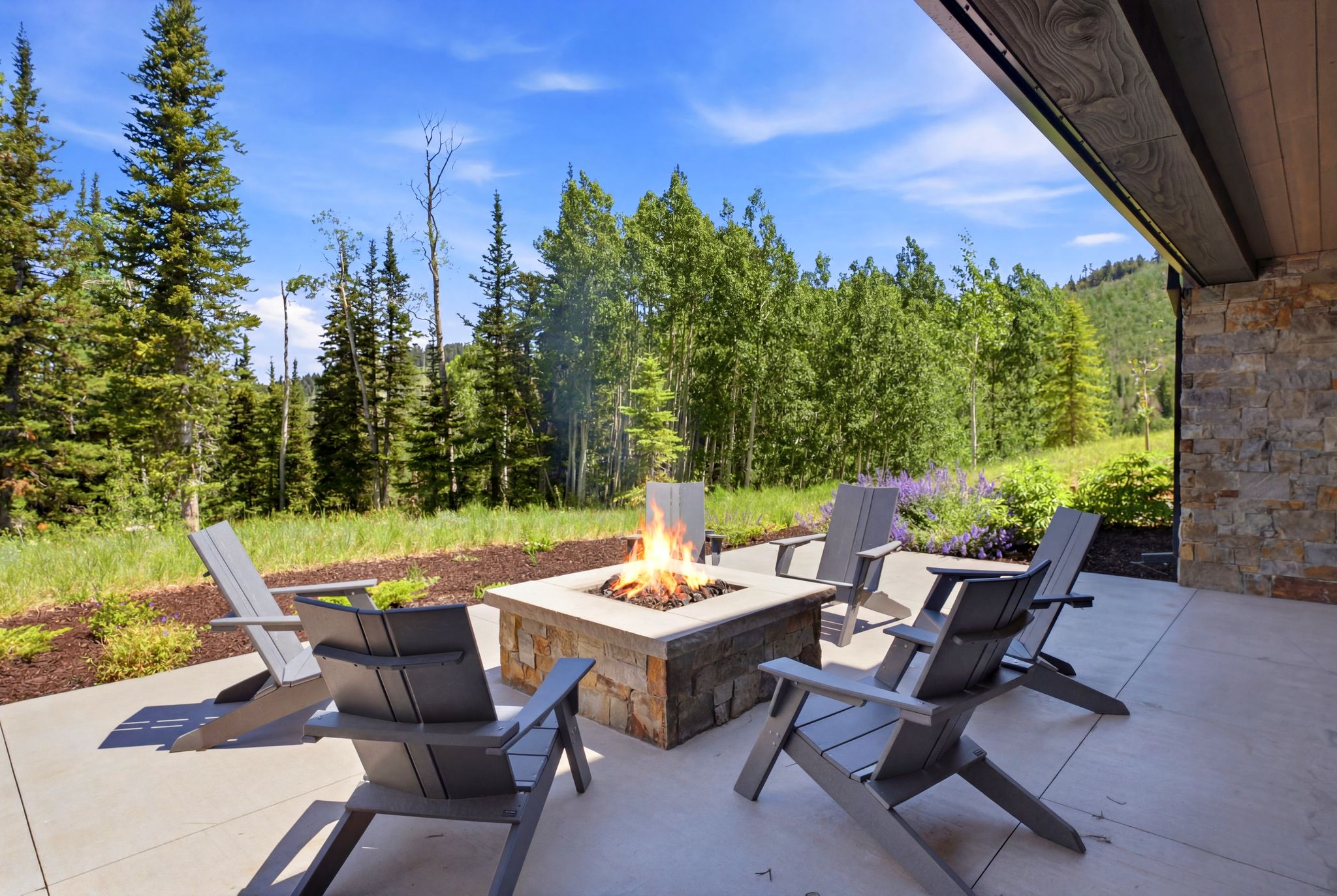 Expansive outdoor patio featuring a stone-clad fire pit with a concrete cap
