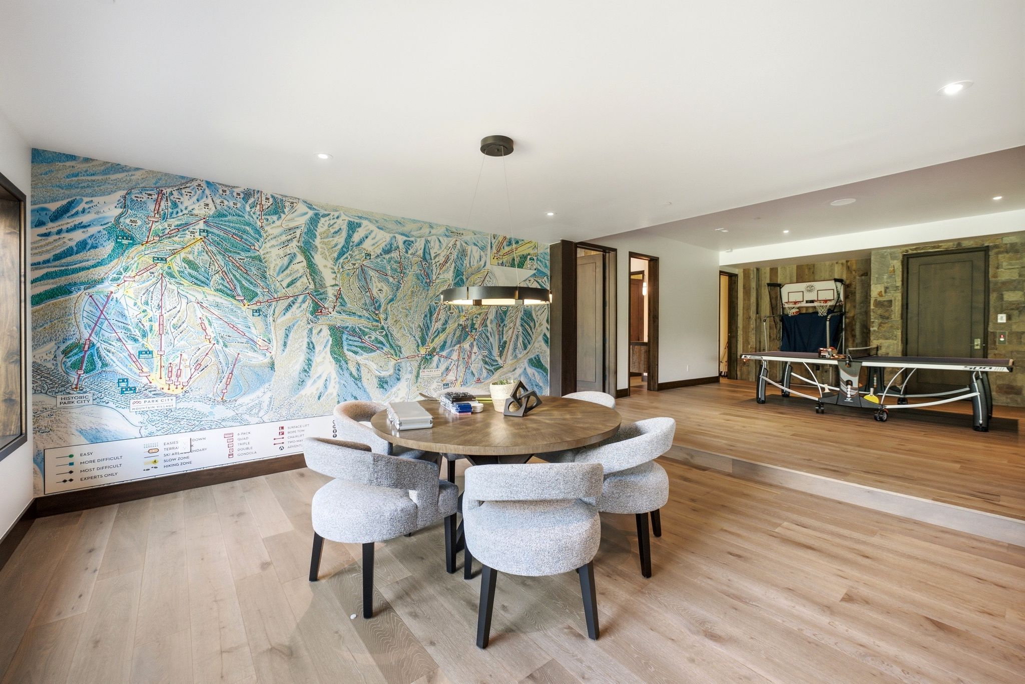 Open concept room featuring a large wall mural, light wood-finish flooring, and a recessed ceiling with integrated lighting