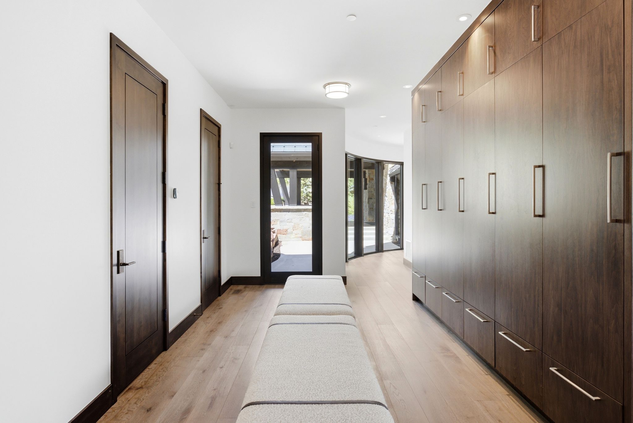 Hallway featuring extensive built-in cabinetry with modern hardware, light wood-finish flooring, and recessed lighting