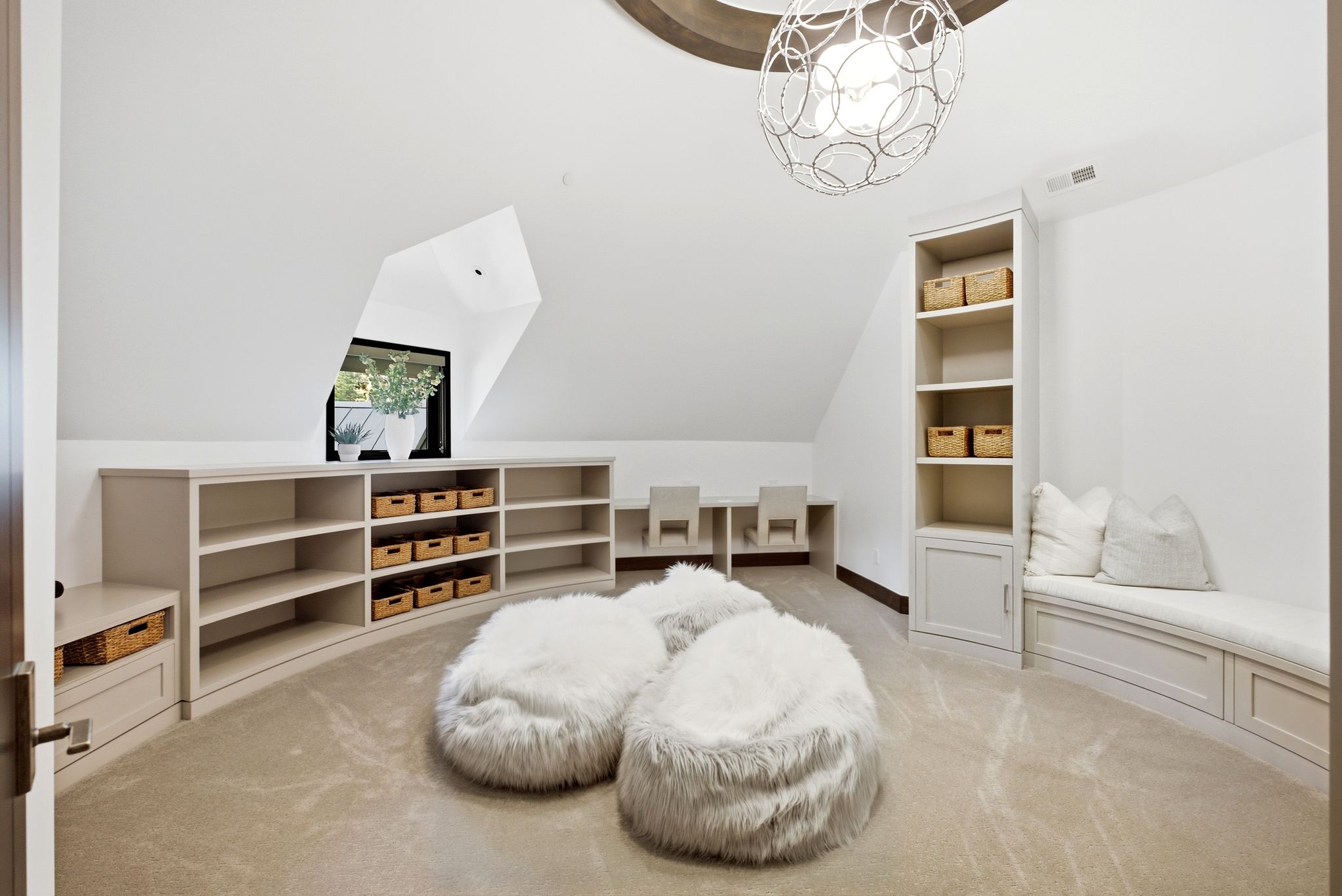 Spacious loft area featuring custom built-in shelving, an arched window, and recessed workspaces