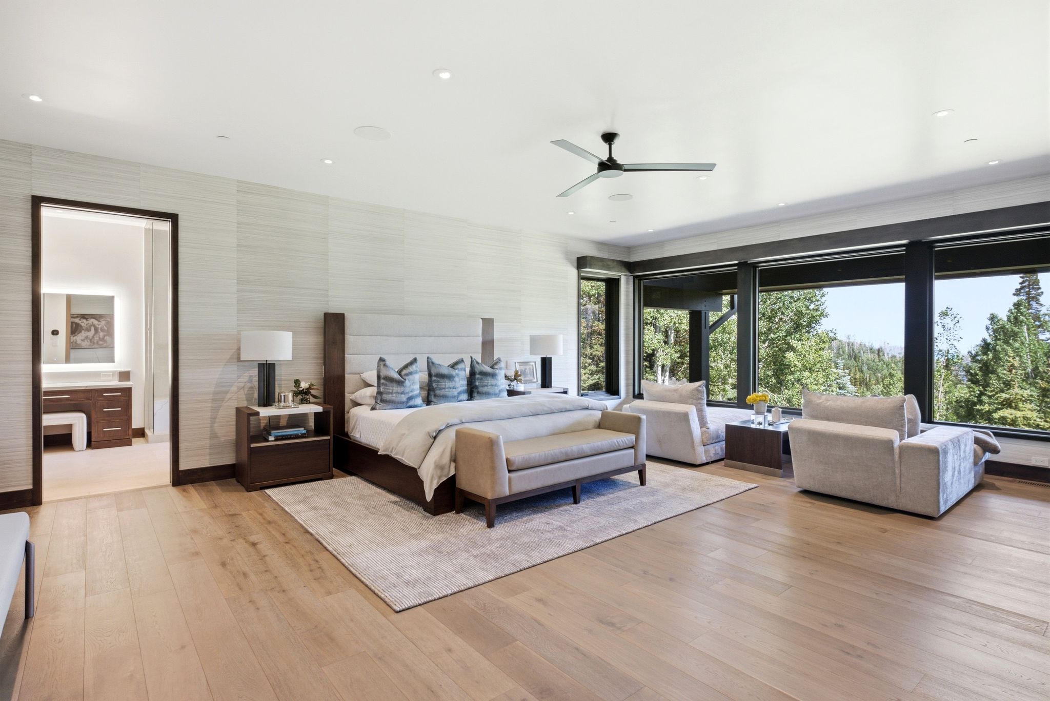 Spacious room featuring light wood-finish flooring and extensive window walls showcasing surrounding trees