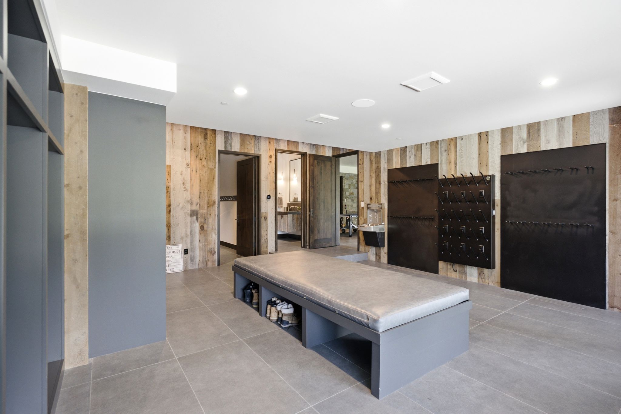 Spacious room featuring wood-finish accent walls, recessed lighting, and large format tile flooring