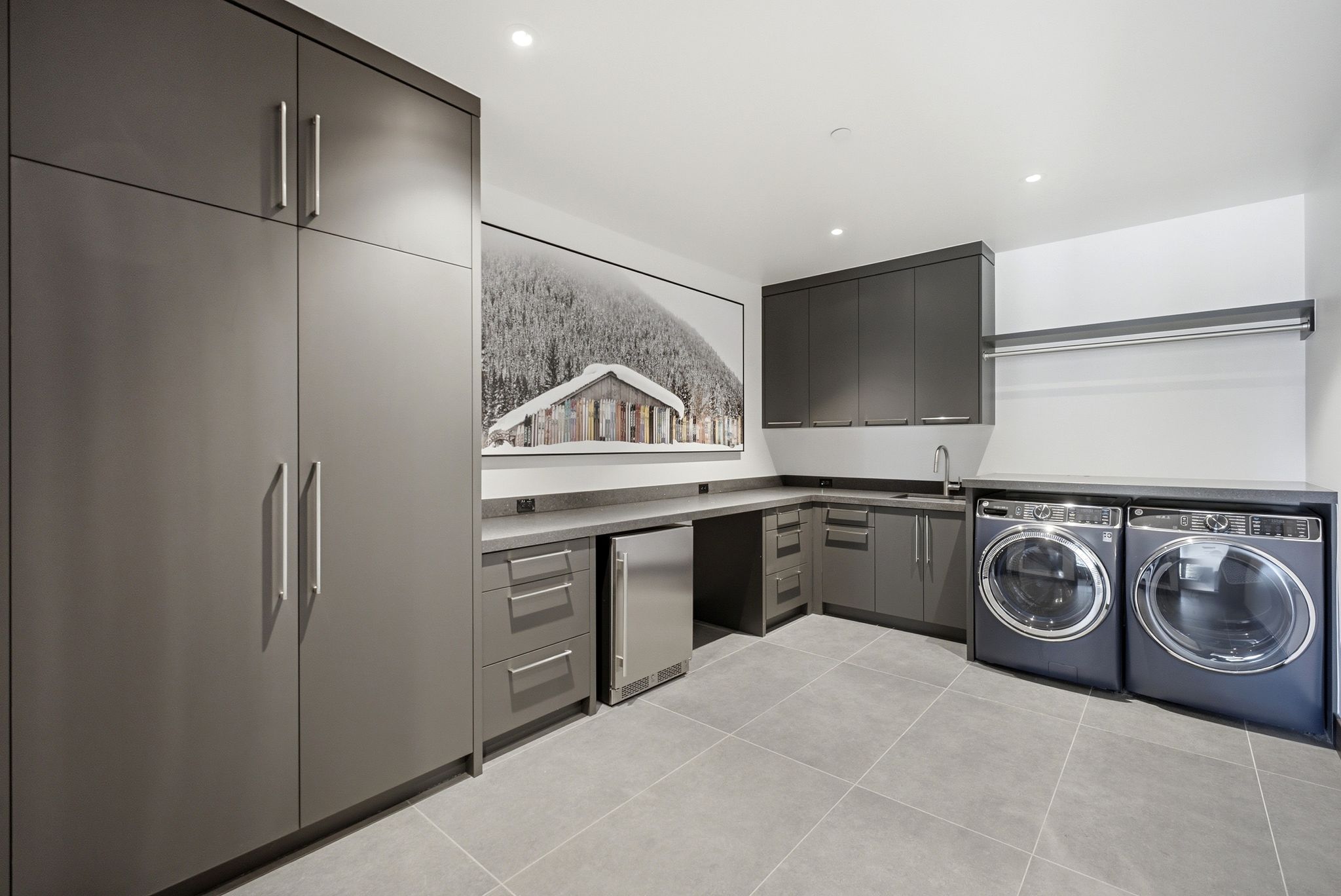 Modern utility space featuring extensive built-in cabinetry, an undermount sink, and integrated appliances