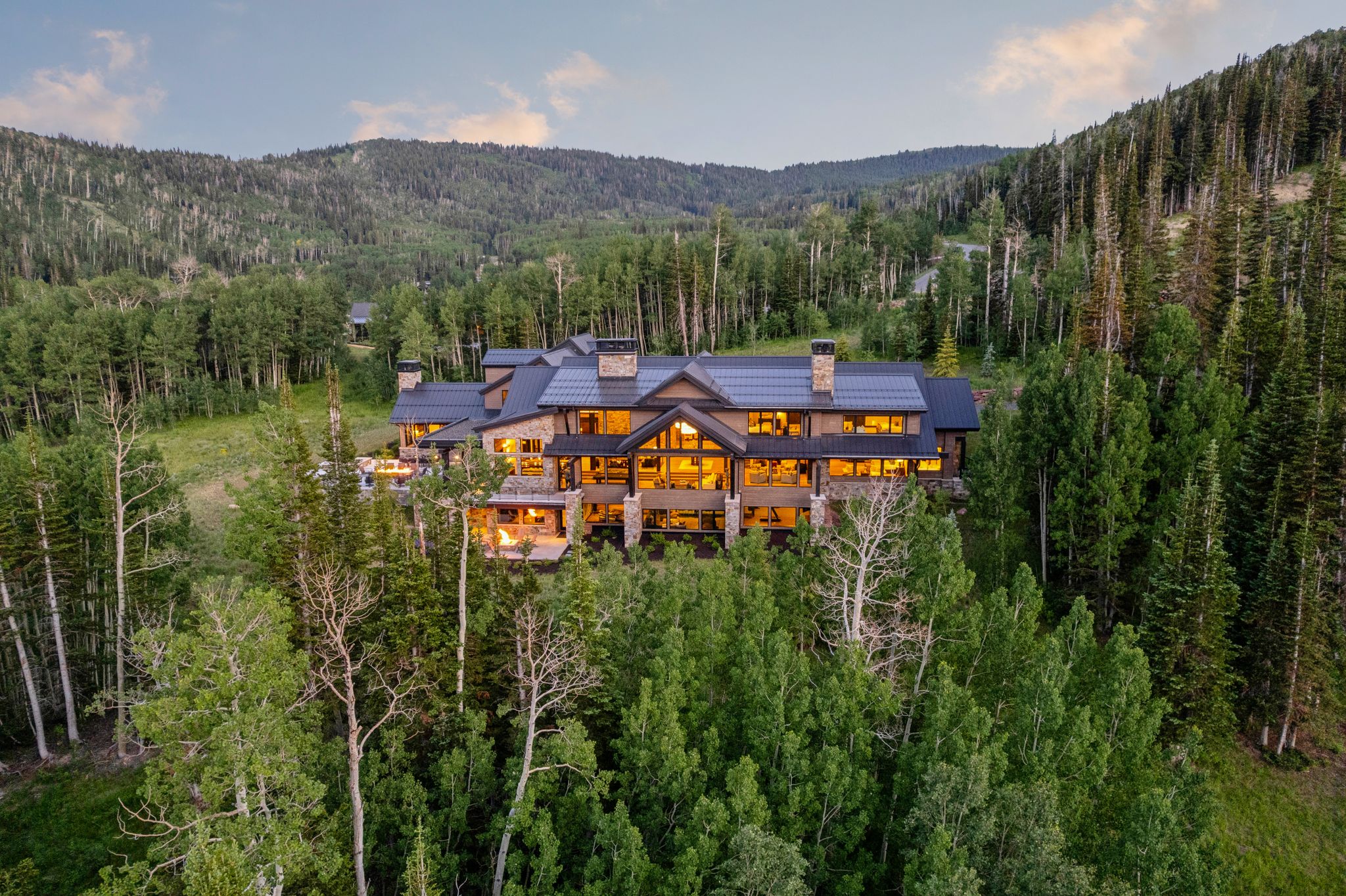 Expansive mountain property featuring a multi-level structure with stone and wood siding, multiple chimneys, and a dark-toned roof