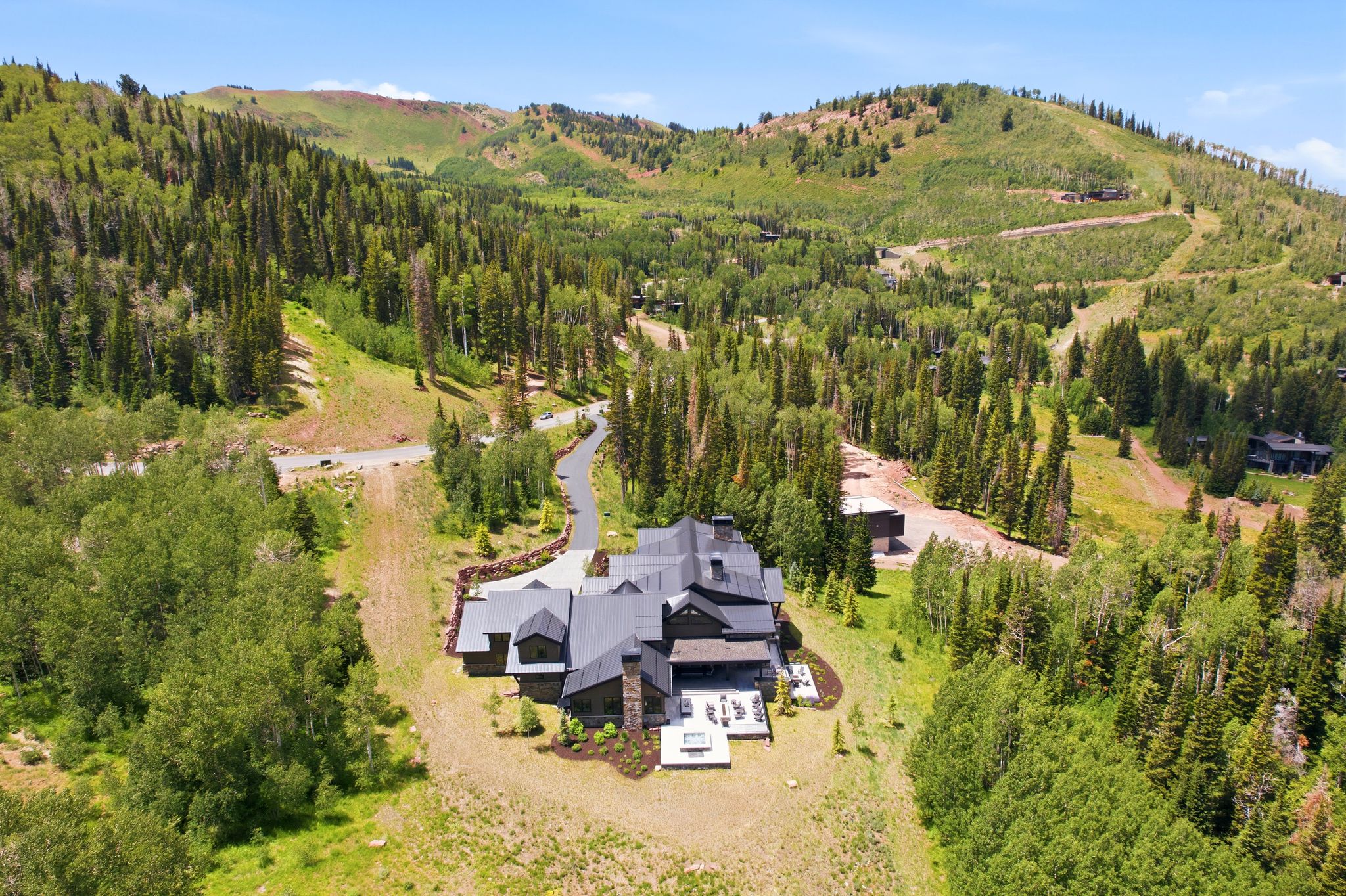 Mountainside residence featuring a multi-gabled dark roofline, stone and dark wood exterior, and an extensive outdoor patio area