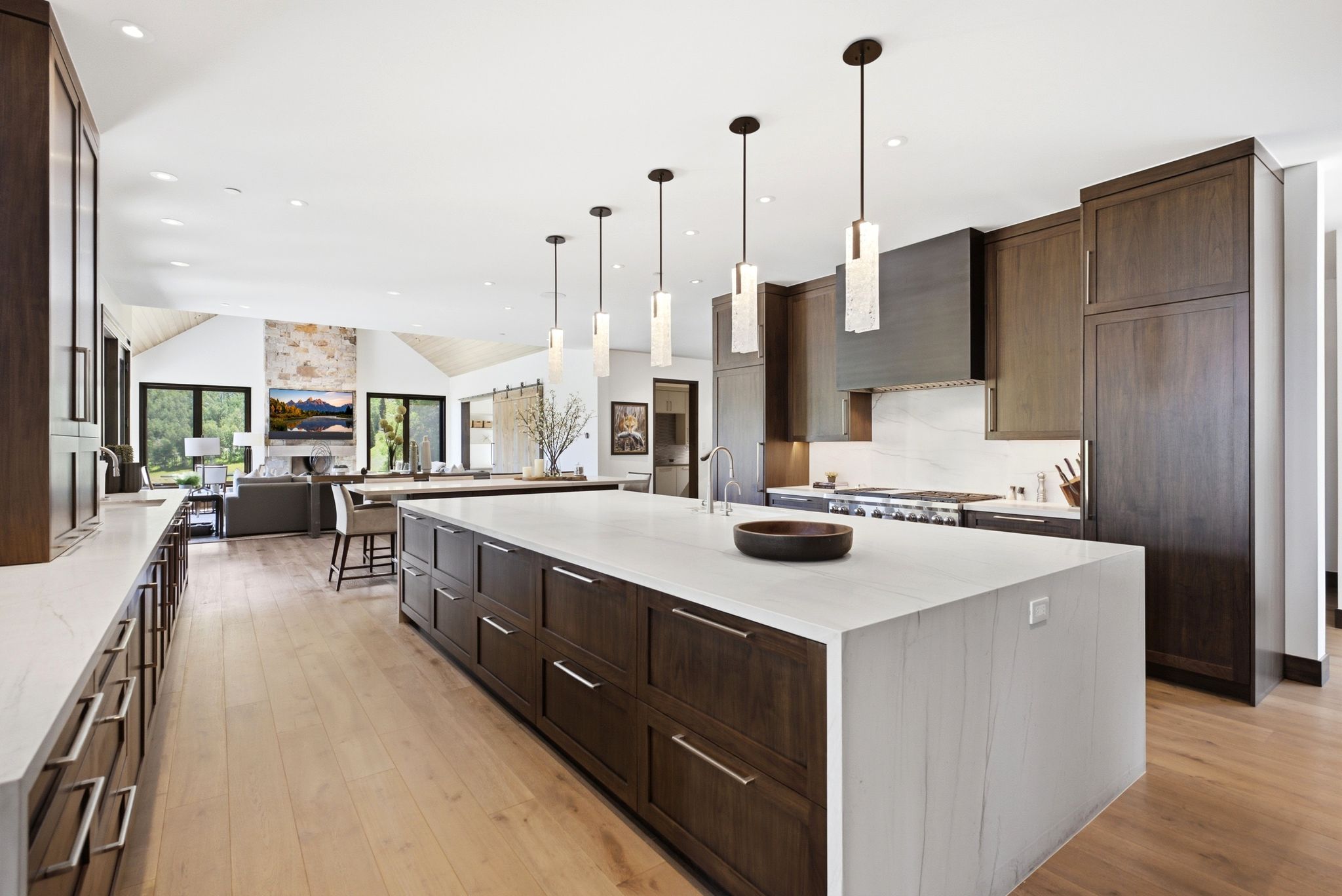 Gourmet kitchen featuring a large central island with seating, dark wood-finish cabinetry, light-toned countertops, and light wood-finish flooring