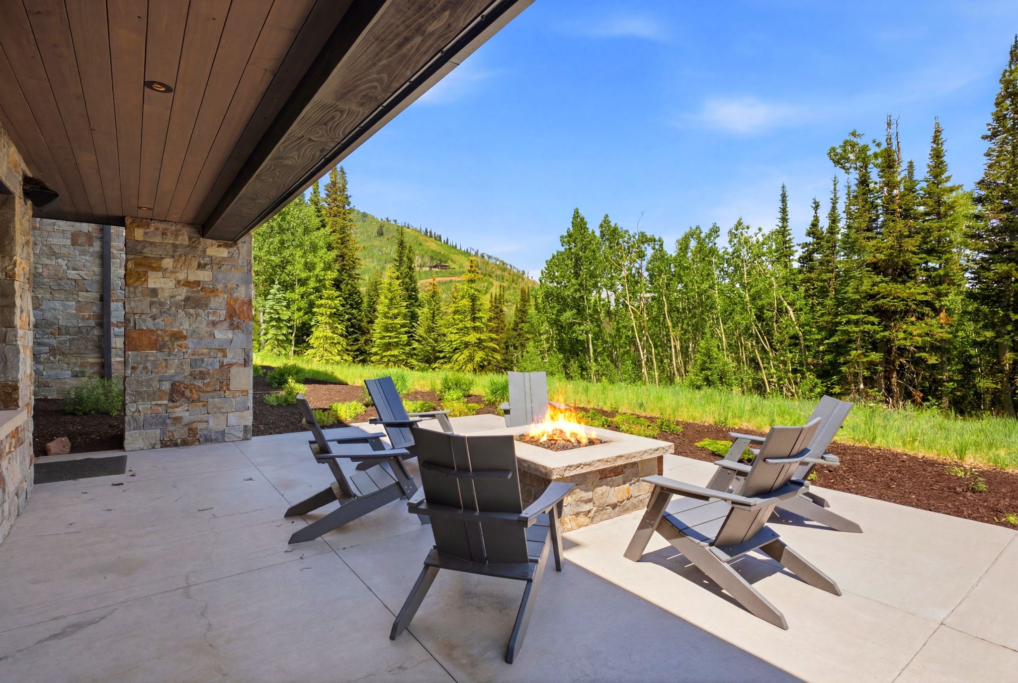 Outdoor patio featuring a stone-clad fire pit, concrete paving, and a timber-paneled ceiling