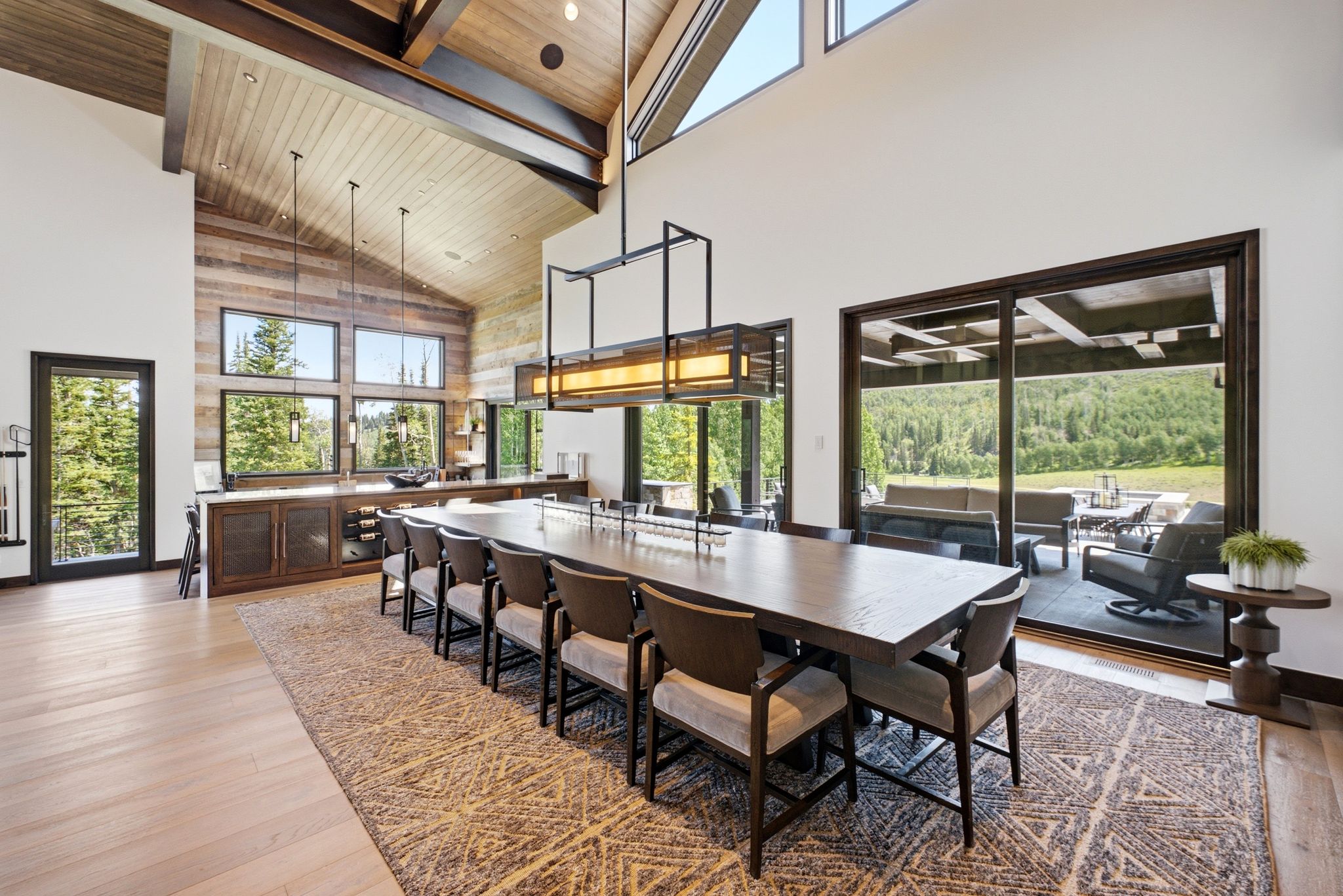 Spacious dining area featuring a vaulted wood-paneled ceiling with exposed beams, light wood-finish flooring, and large windows