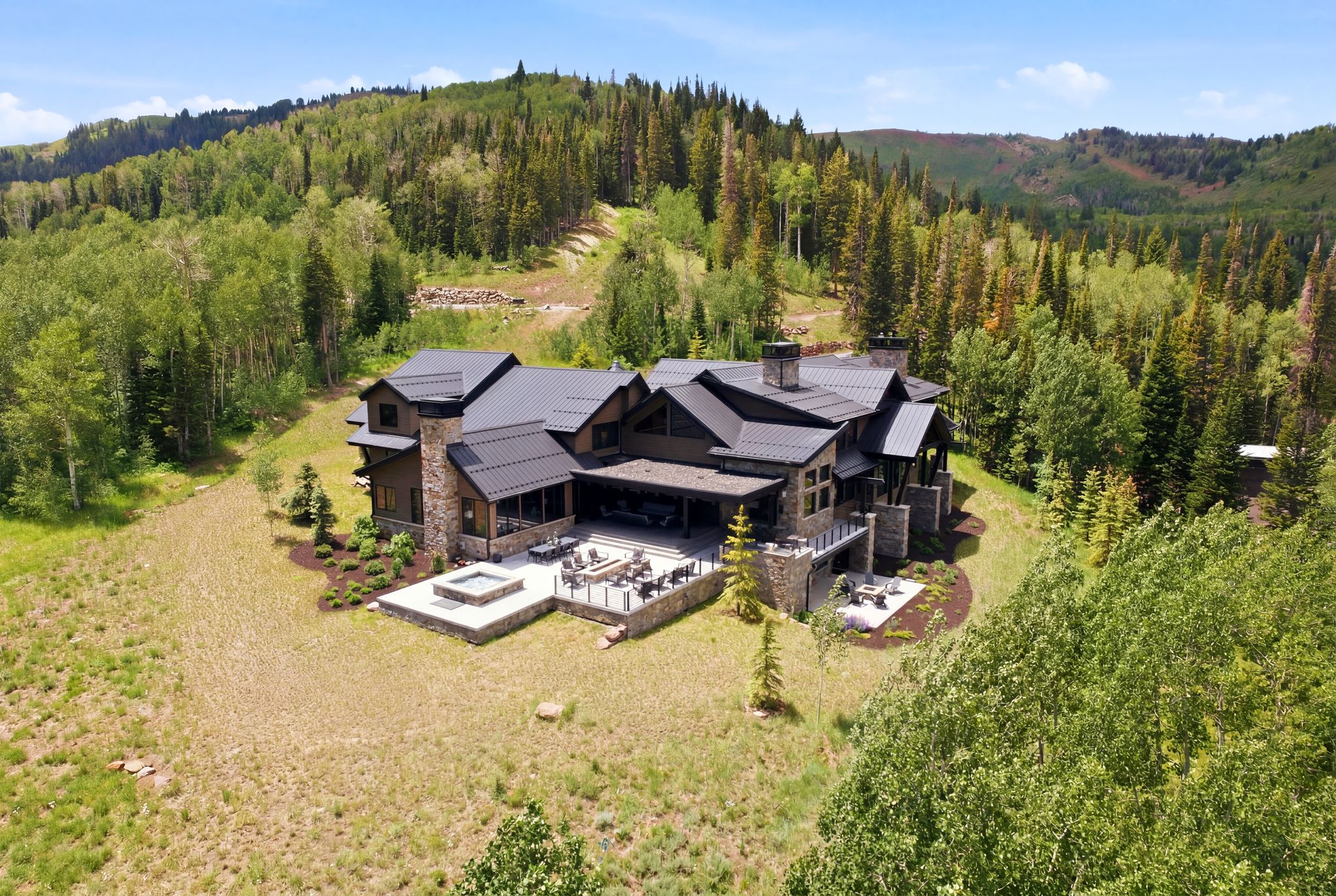 Sprawling multi-level residence featuring a dark metal roof, stone accents, and expansive outdoor patio spaces