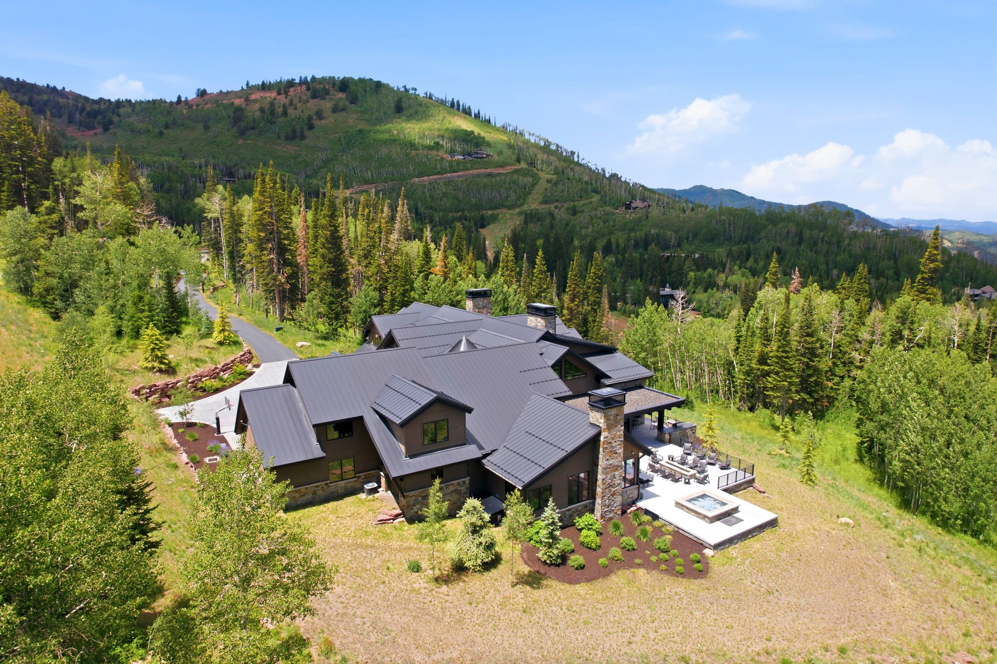 Contemporary mountain residence featuring a dark metal roof, stone and wood-paneled exterior, and multiple chimneys