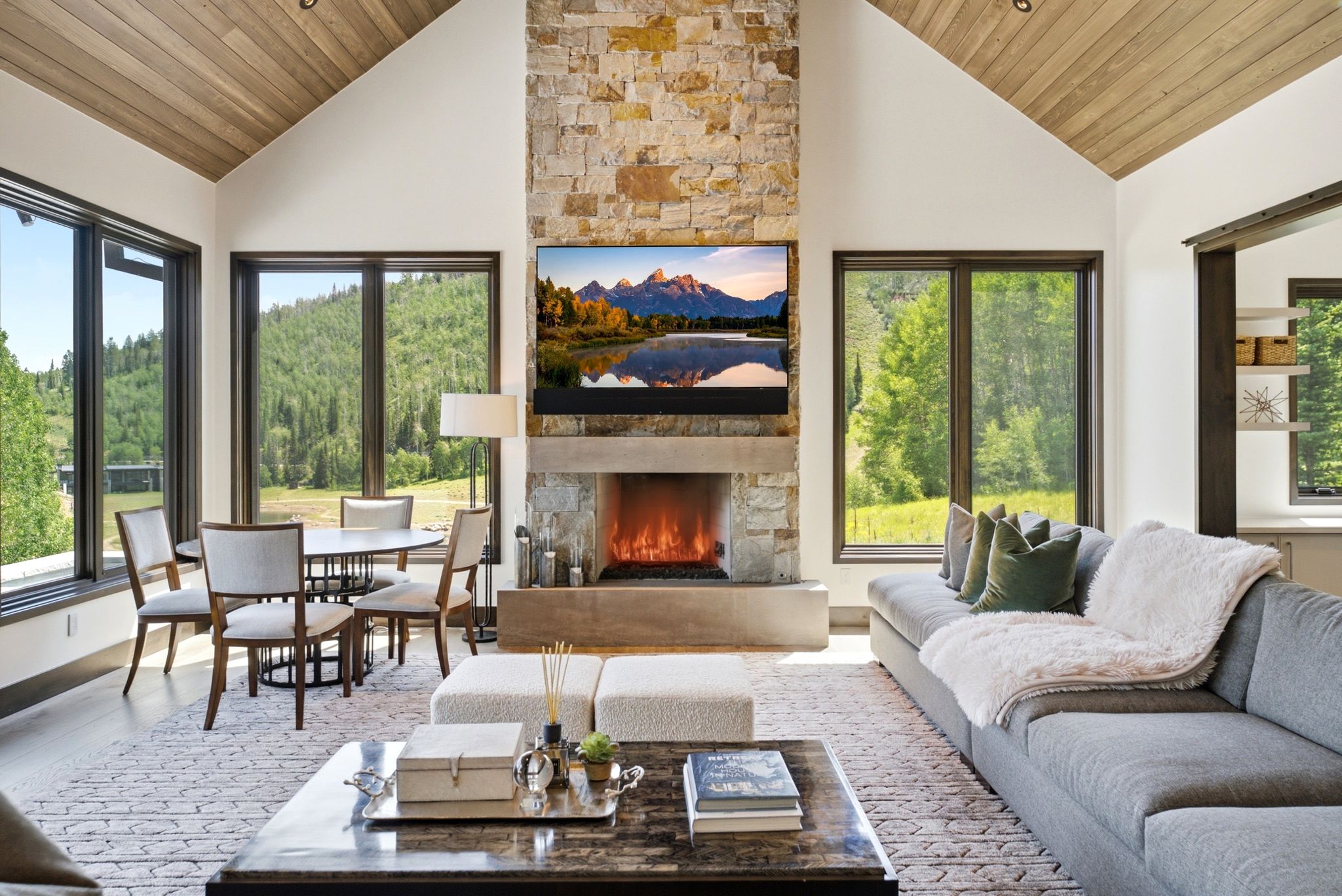 Great room featuring a floor-to-ceiling stone fireplace, a vaulted wood-finish ceiling, and large picture windows