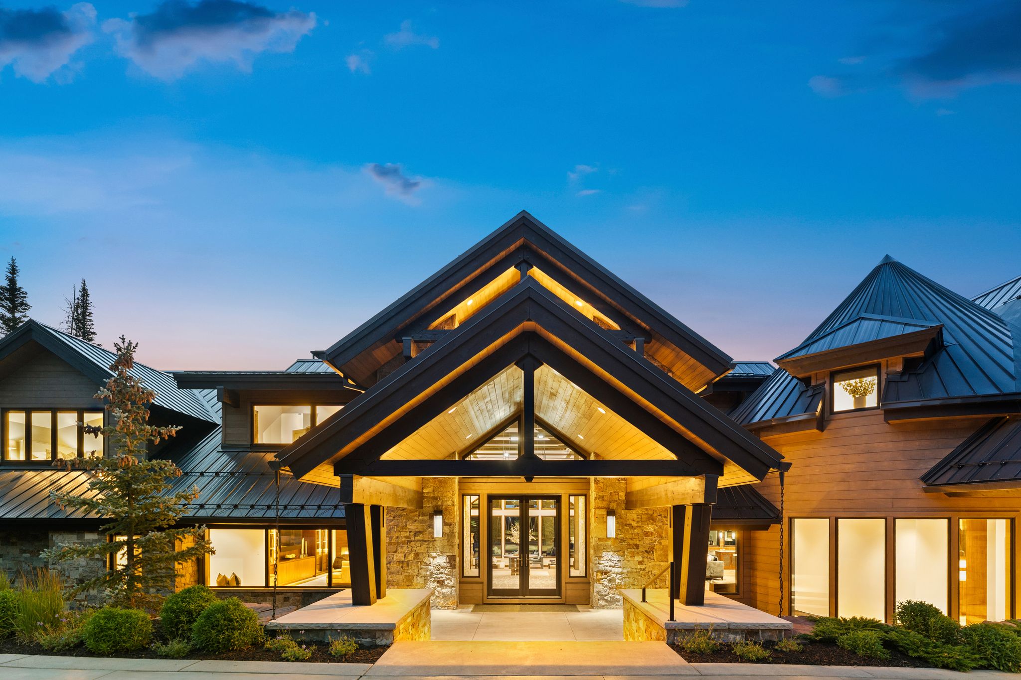 Striking architectural exterior featuring a prominent gabled entrance with exposed wood soffits and an integrated lighting system