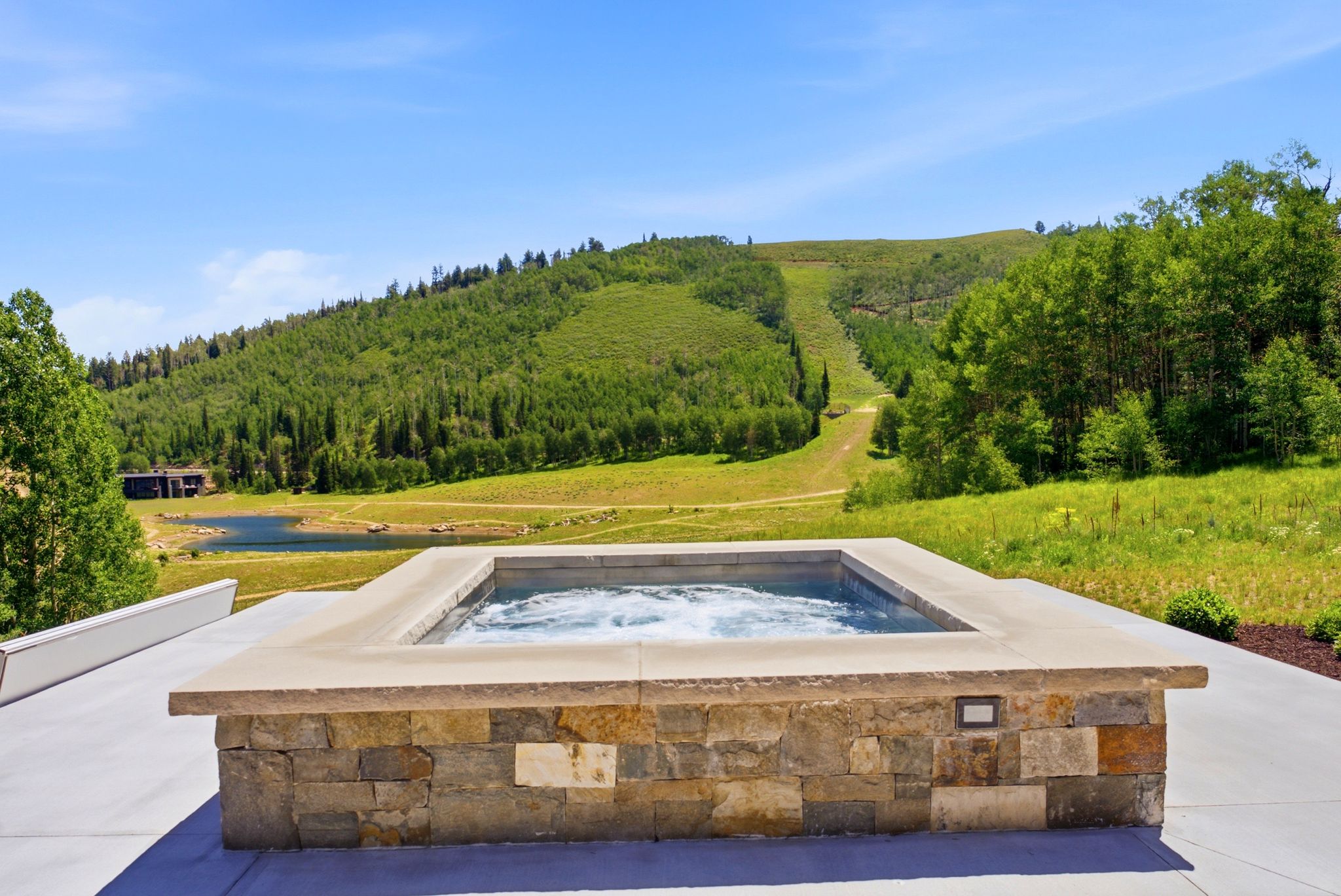 Built-in spa with natural stone surround and a concrete patio