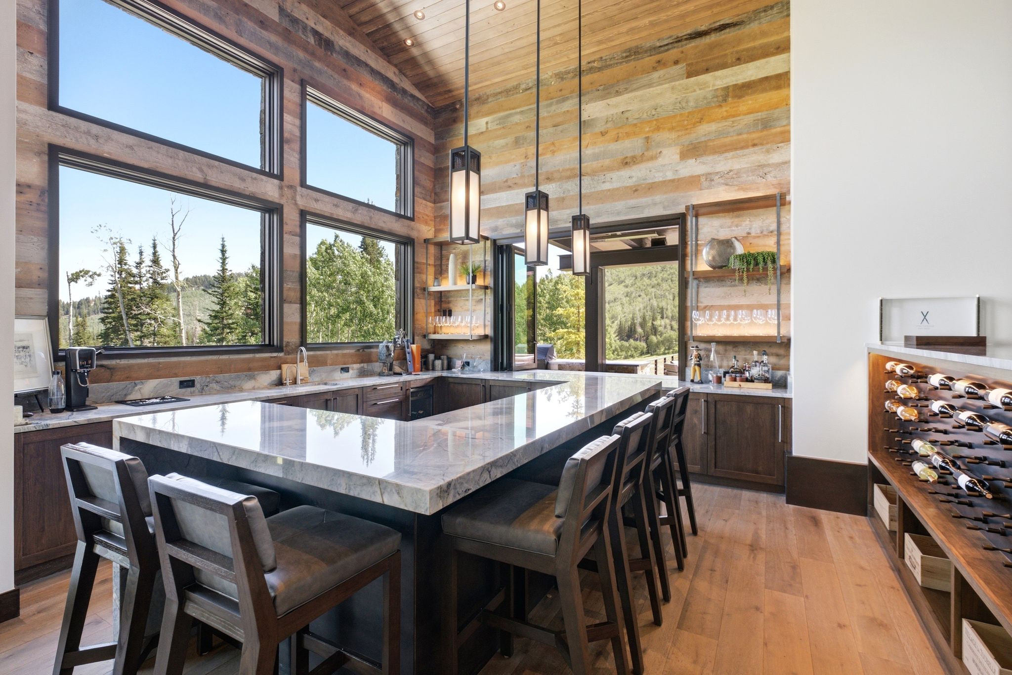 Spacious kitchen featuring a large U-shaped island with seating, natural wood-finish flooring, and a vaulted ceiling with exposed wood paneling