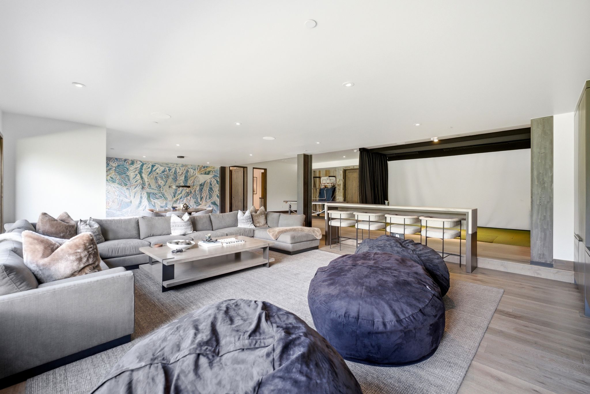 Expansive entertainment area featuring recessed lighting, light wood-finish flooring, and a large projection screen