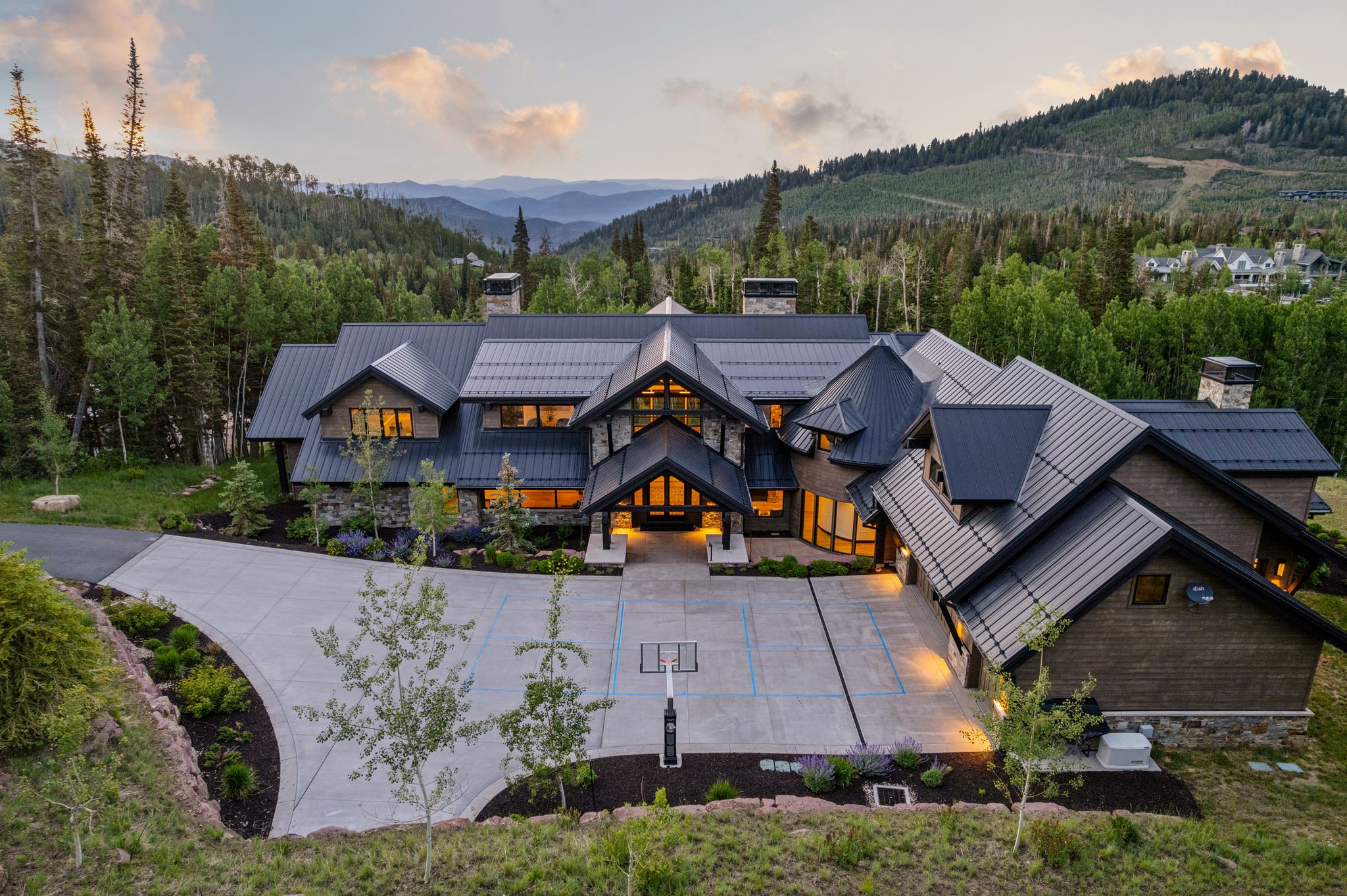 Sprawling modern mountain residence featuring a multi-gabled metal roof, stone accents, and extensive landscaping