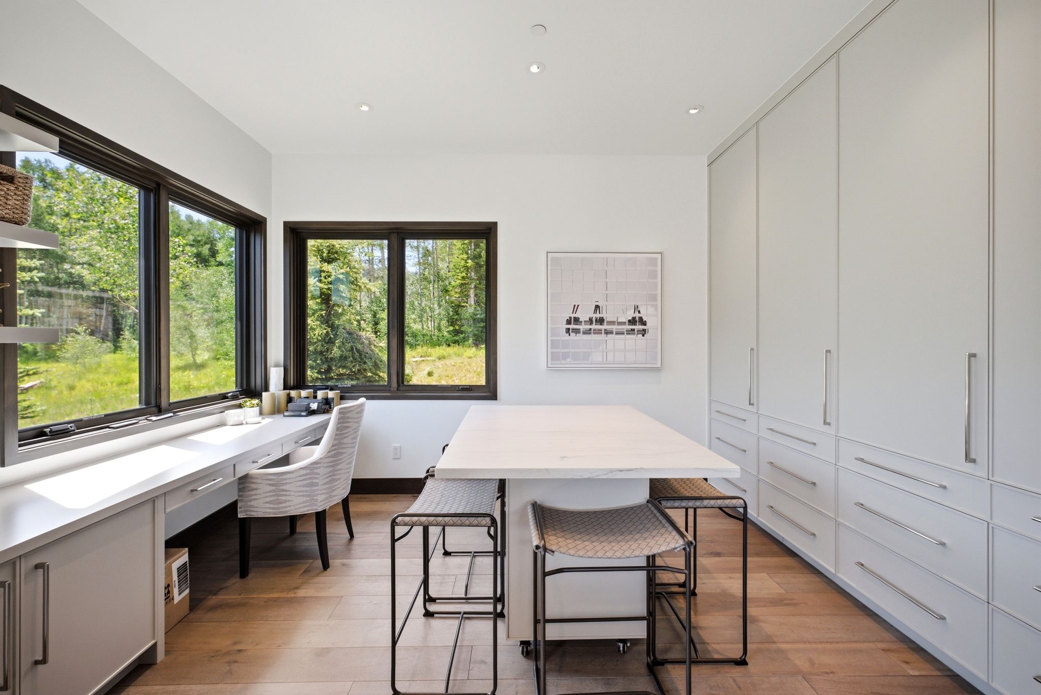 Dedicated workspace featuring expansive windows, built-in desk cabinetry, light wood-finish flooring, recessed lighting, and extensive built-in storage