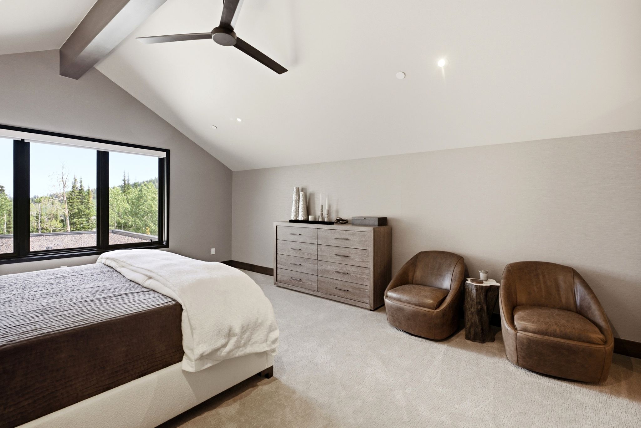 Vaulted ceilings with exposed beams and a modern ceiling fan define this space